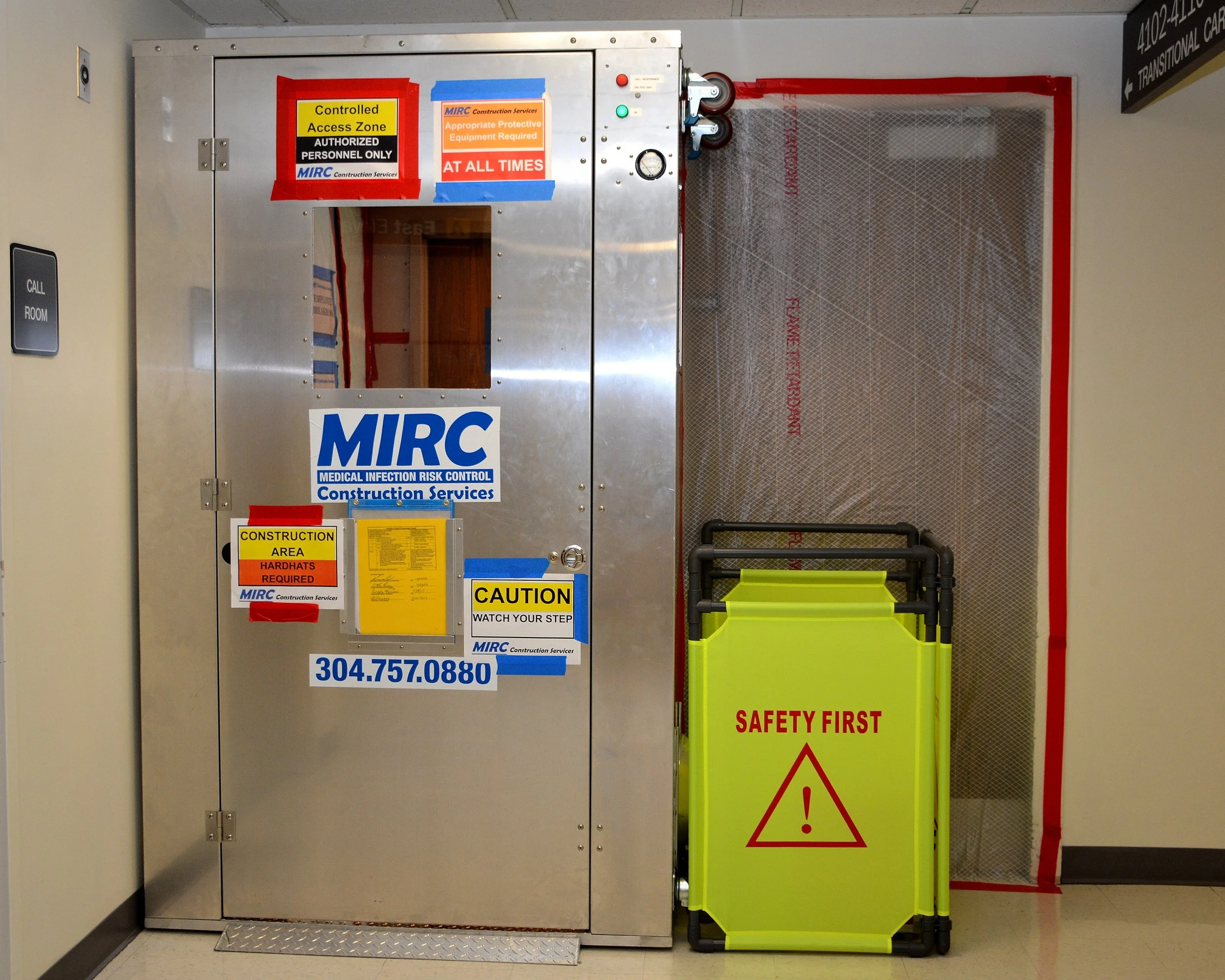Temporary construction anteroom with controlled-access signage, personal protective equipment requirements and safety notices.