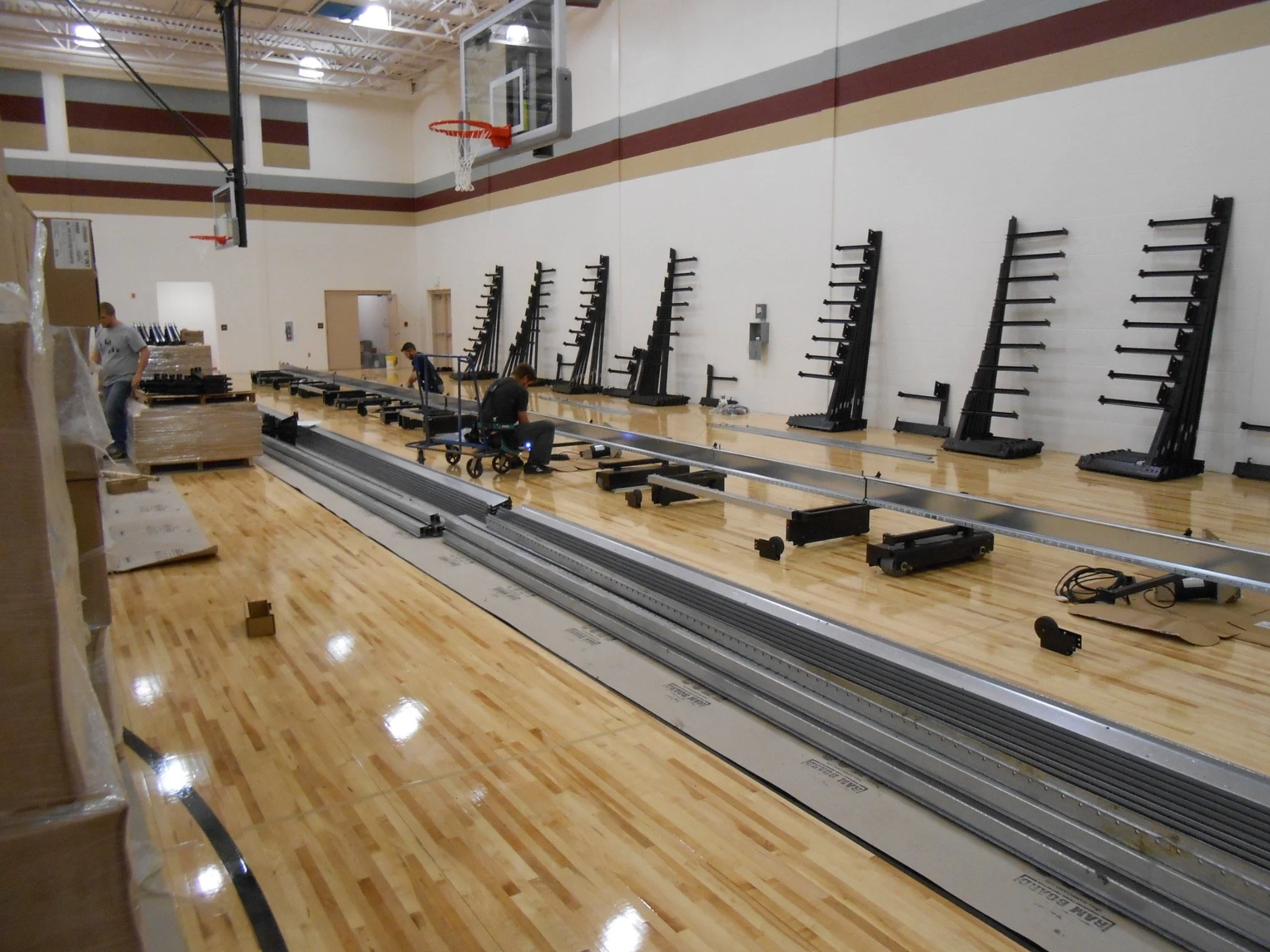 Mingo County school gymnasium during construction with telescoping bleachers, basketball equipment and interior finish work underway.