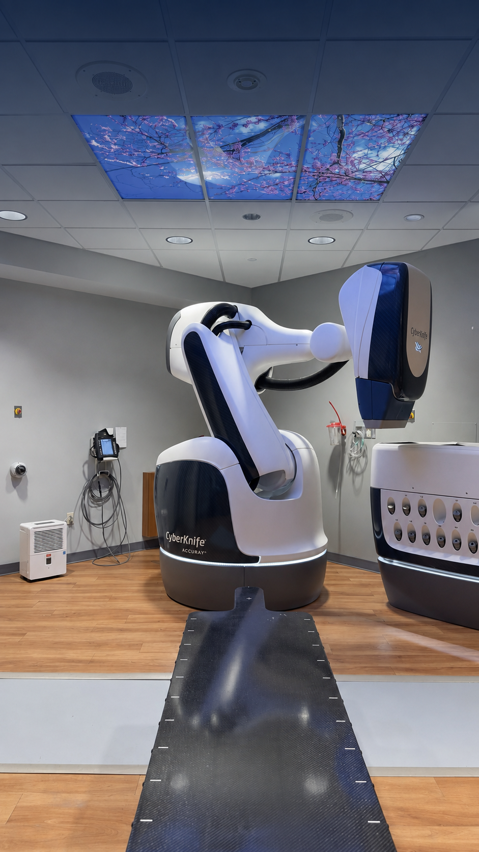 Accuray CyberKnife S7 radiation-treatment system beneath illuminated cherry-blossom ceiling panels at St. Mary’s Medical Center.