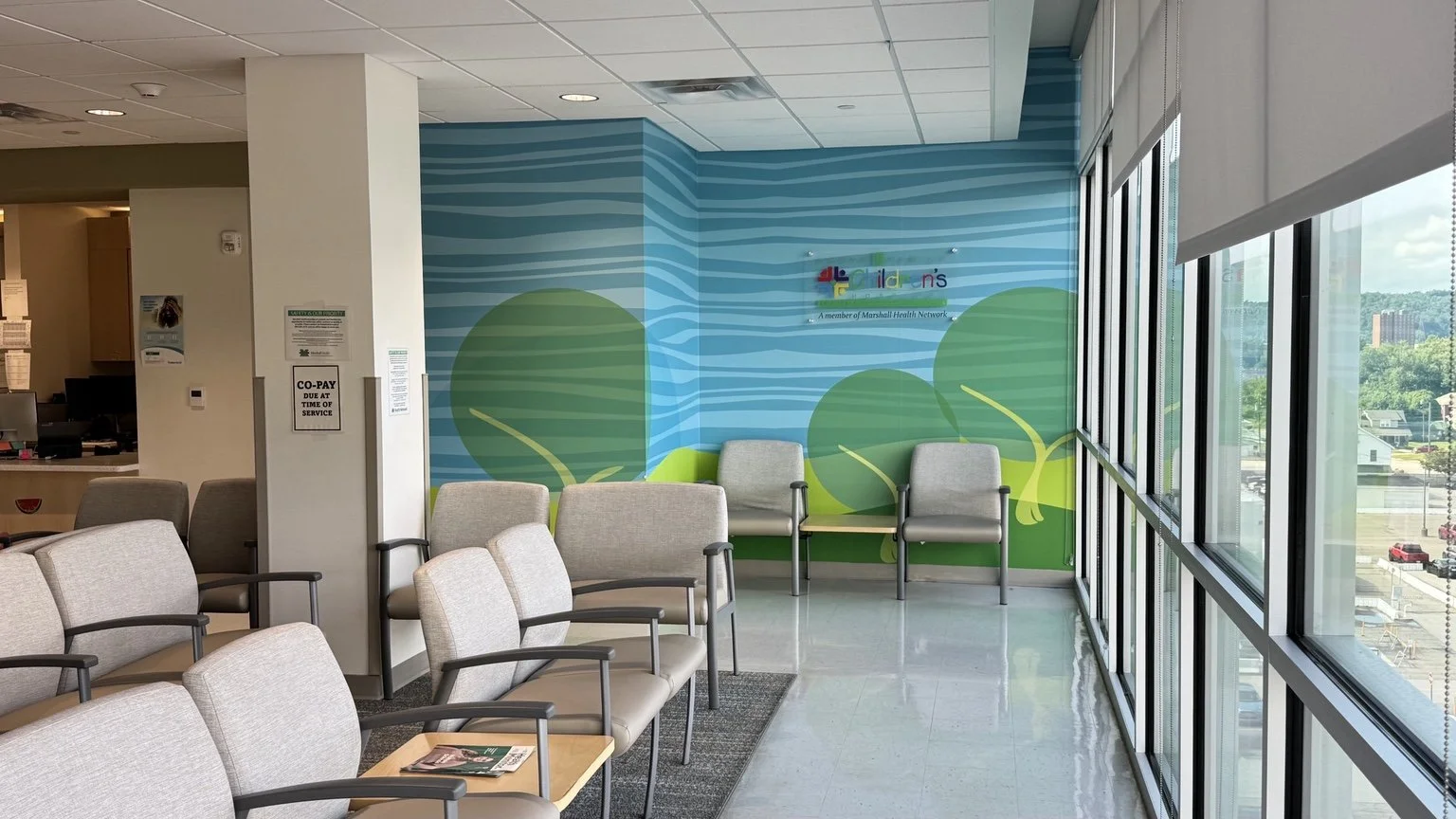 Robert & Lena Shell Medical Pavilion - Children’s healthcare waiting area with colorful wall graphics, seating, and natural light.