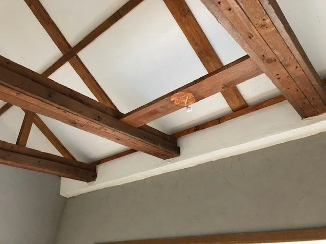 Holzträger und Deckenbalken in einem Raum unter Renovierung oder Bau, mit sichtbarer Dämmung.