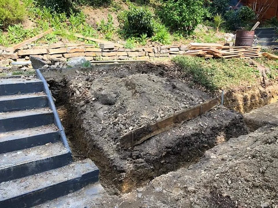 Aufforstungs- oder Baugrube neben einer Treppe mit Bauwerkzeugen und Holzplatten