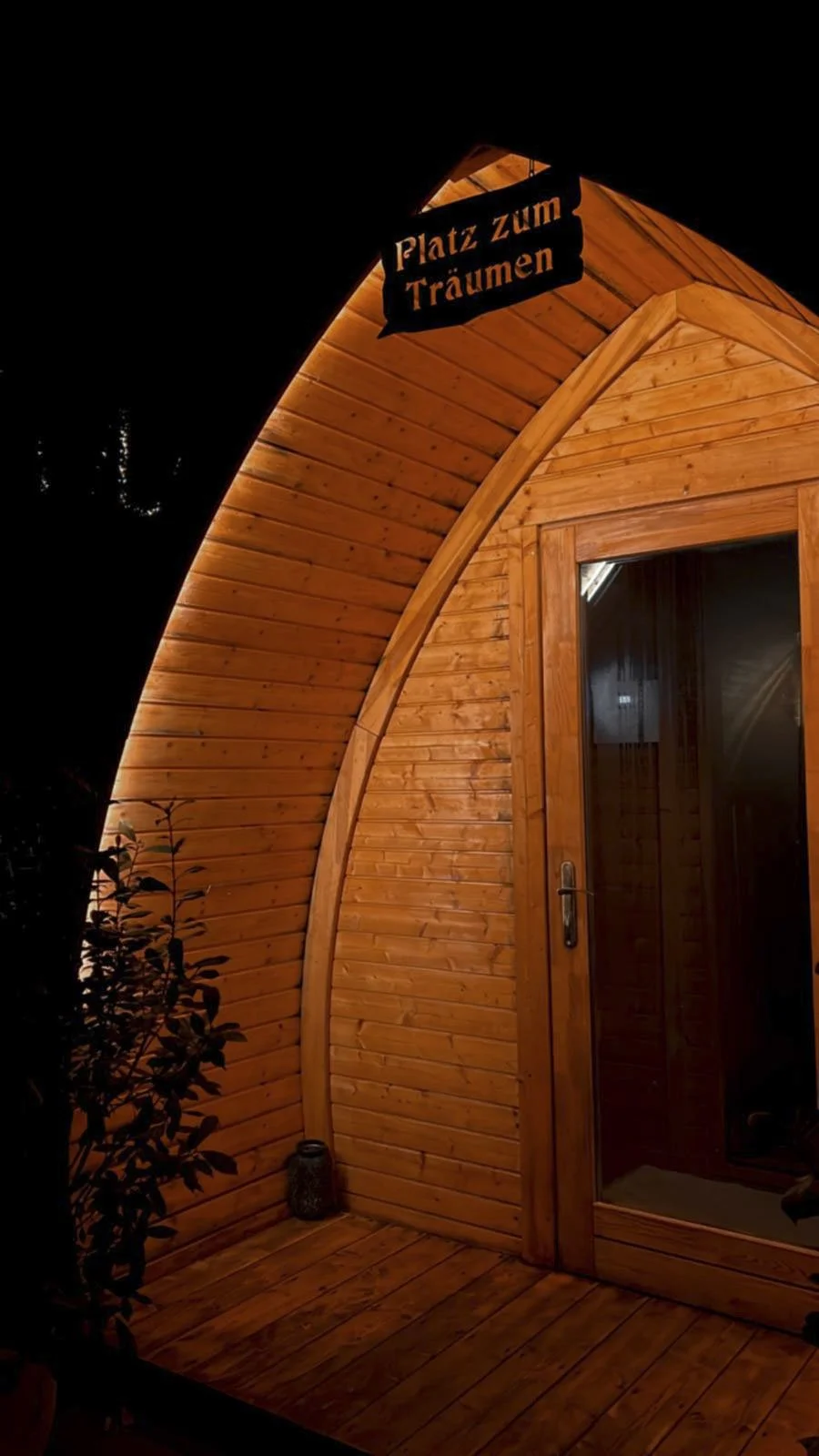 Ein Holzhaus bei Nacht mit einem Aufhänger, der 'Platz zum Träumen' sagt.