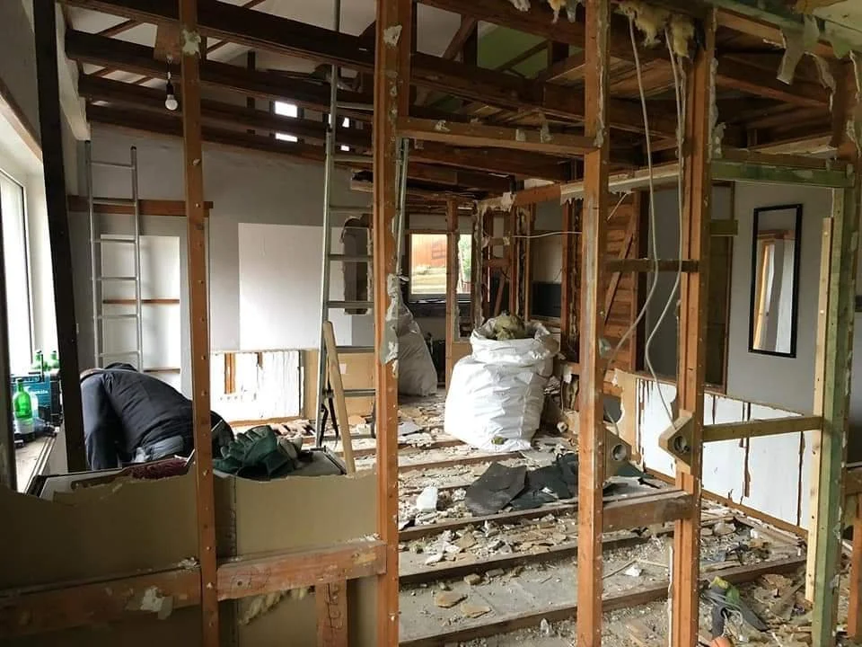 Innenraum eines Hauses in Renovierung oder Umbau, mit sichtbaren Holzkonstruktionen, Baumaterialien und Bauutensilien.