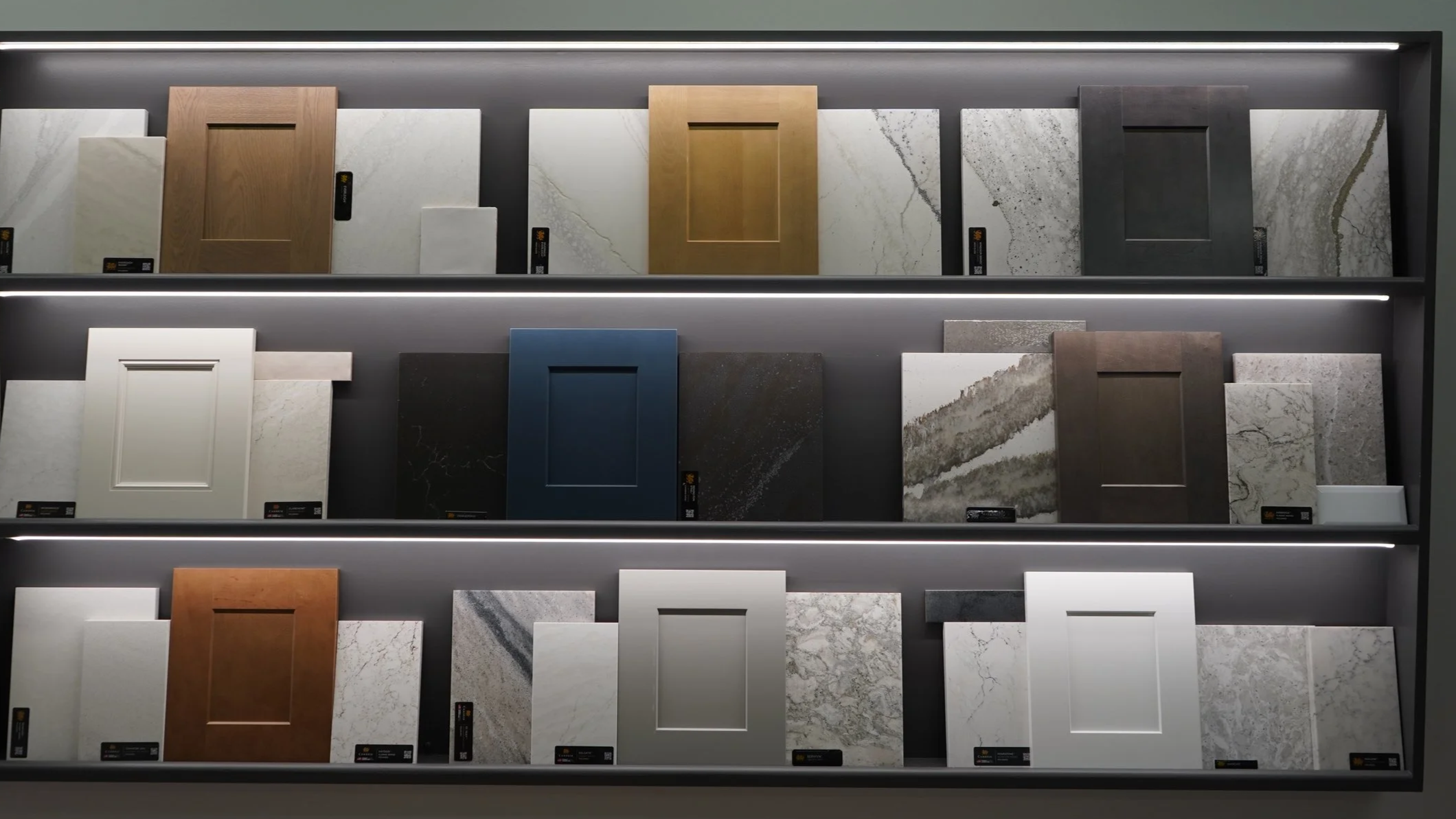 Display of various sample cabinet door styles and colors in a showroom with three shelves