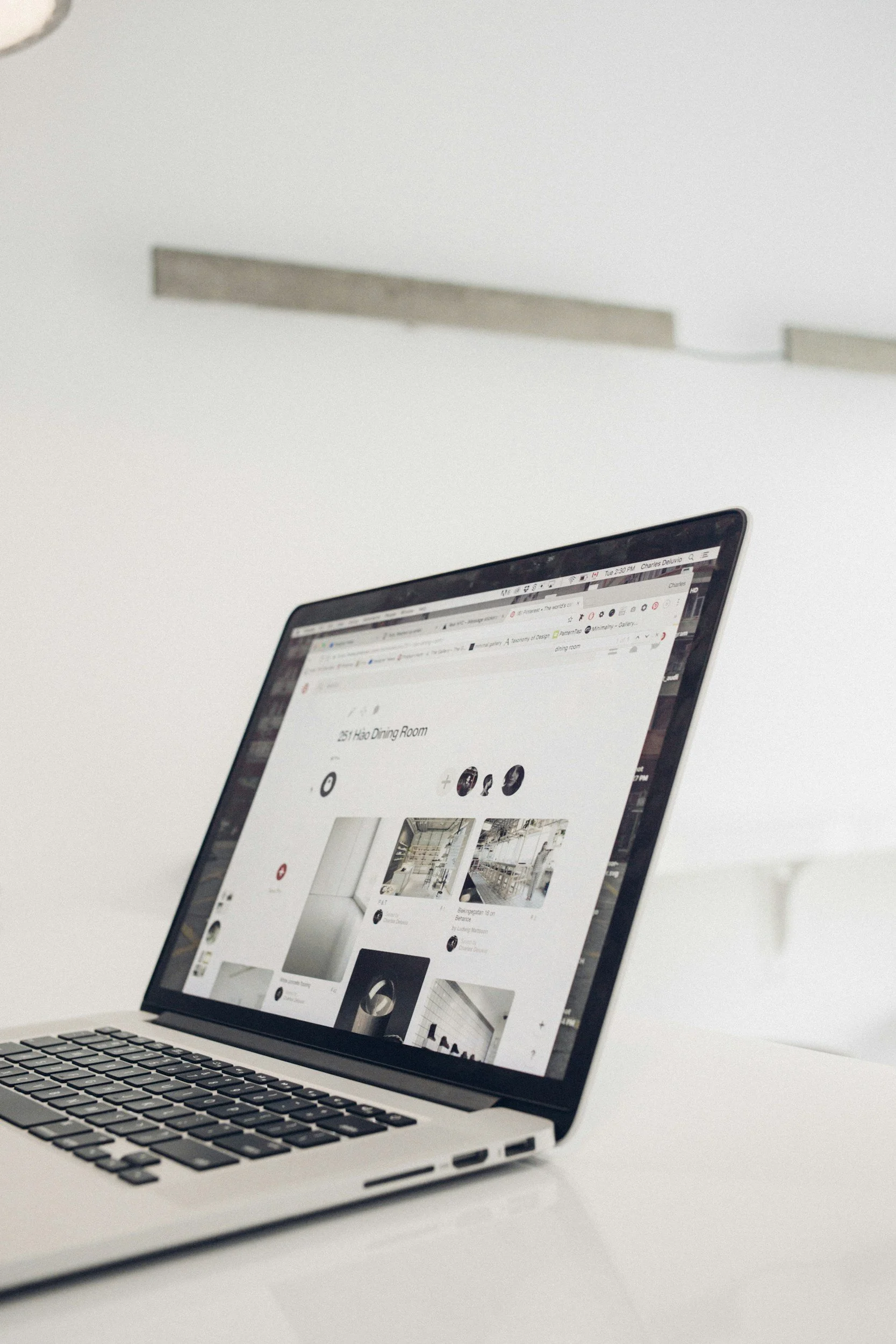 A laptop on a white desk displaying a webpage with images and text.