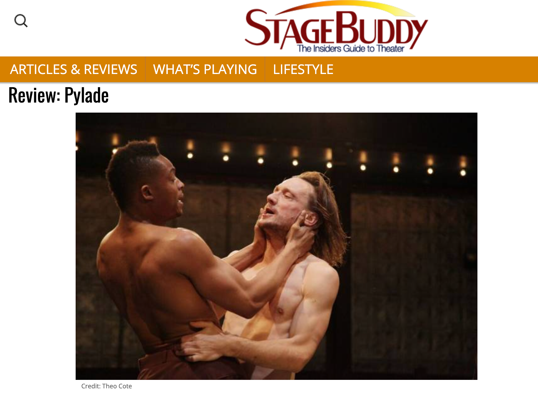 Two shirtless men, one with dark skin and short hair, the other with lighter skin and long hair, are dancing closely together in a dimly lit room, with warm spotlights above.
