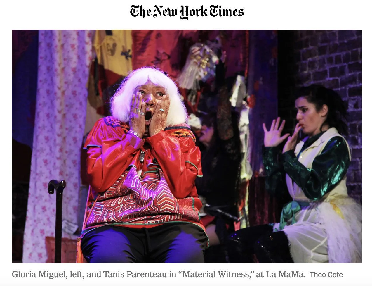 Gloria Miguel and Tanis Parenteau acting in a theatrical performance titled "Material Witness" at La MaMa theater, showing expressive gestures and colorful costumes.