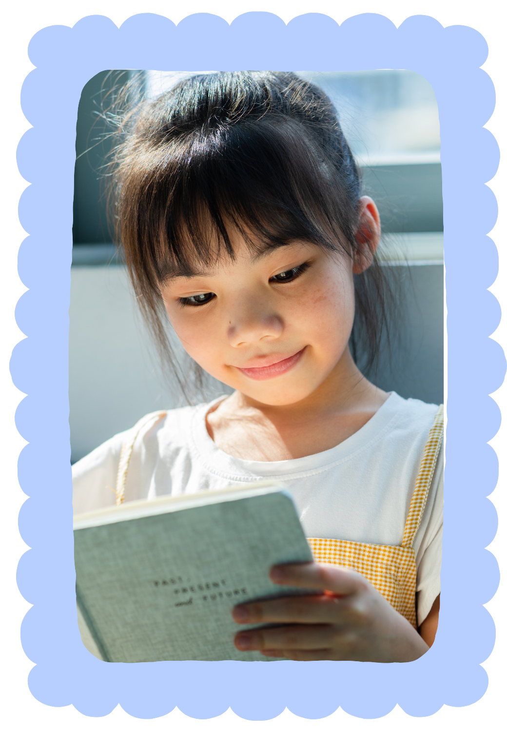 A young girl with dark hair and freckles working on reading a book during in-home literacy therapy for kids in New York City.