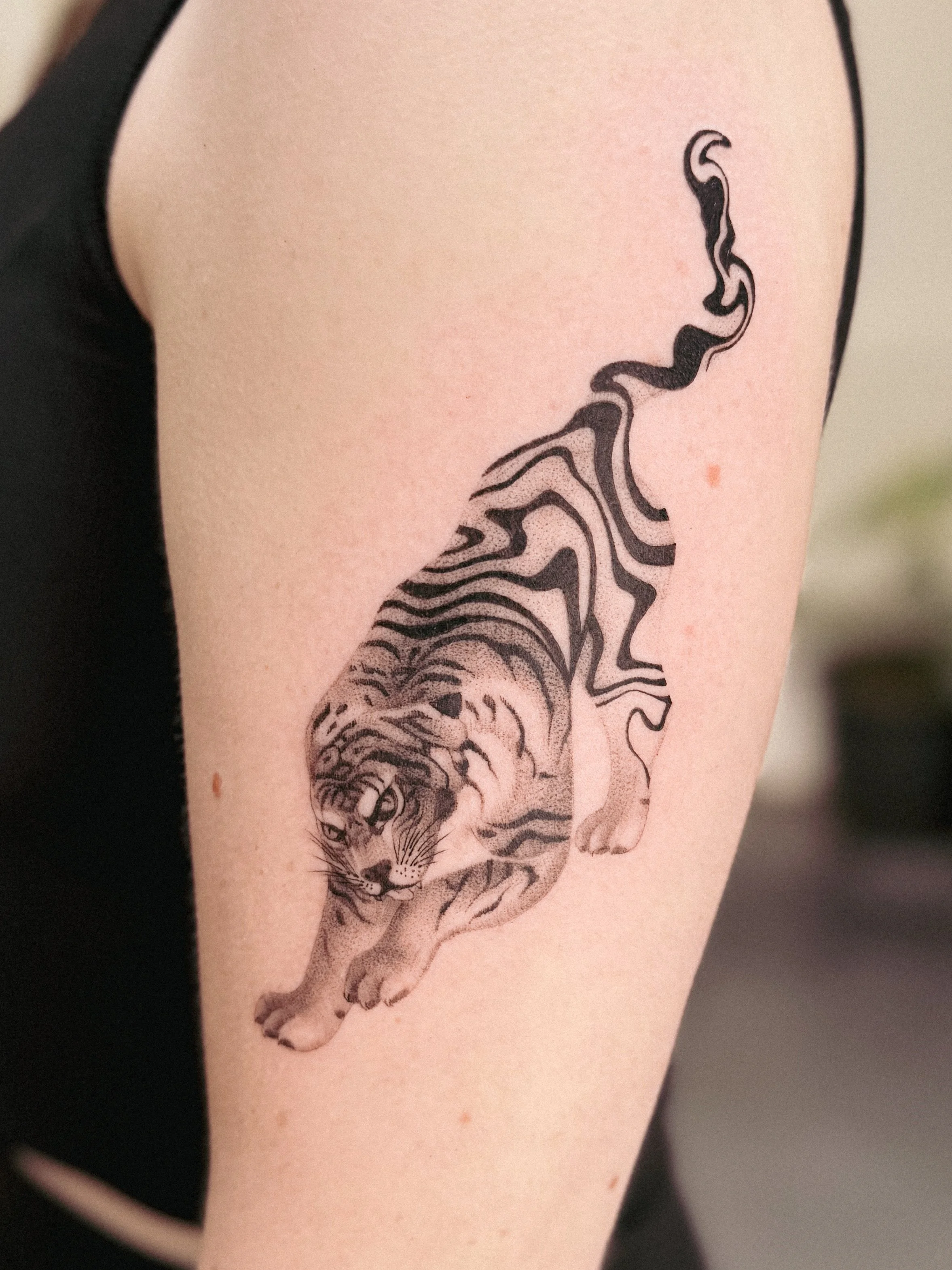 Tattoo of a tiger on a person's arm, with detailed black and white line art.