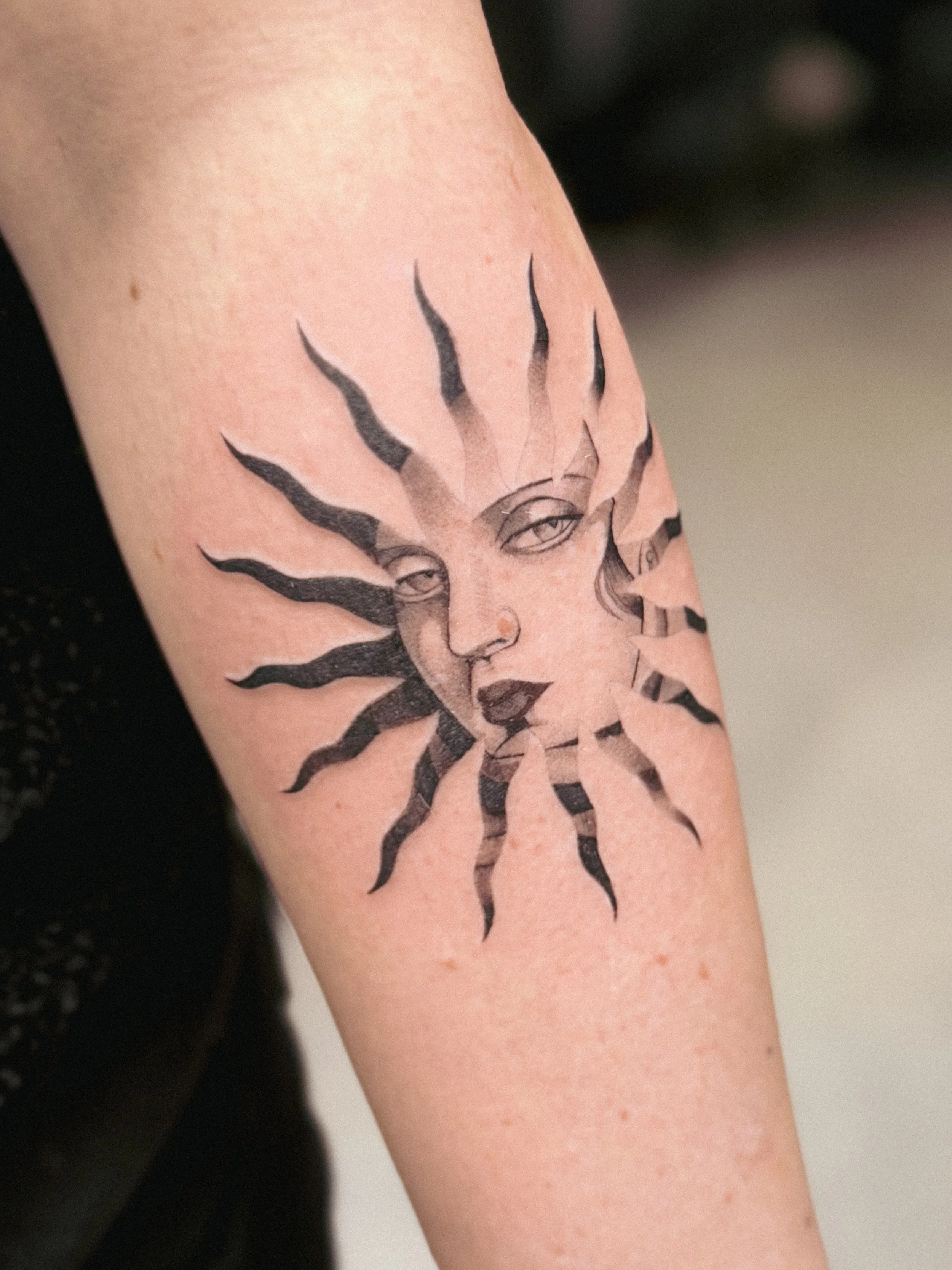 Tattoo of a sun with a face on a person's arm. sun lempicka tamara tattoo