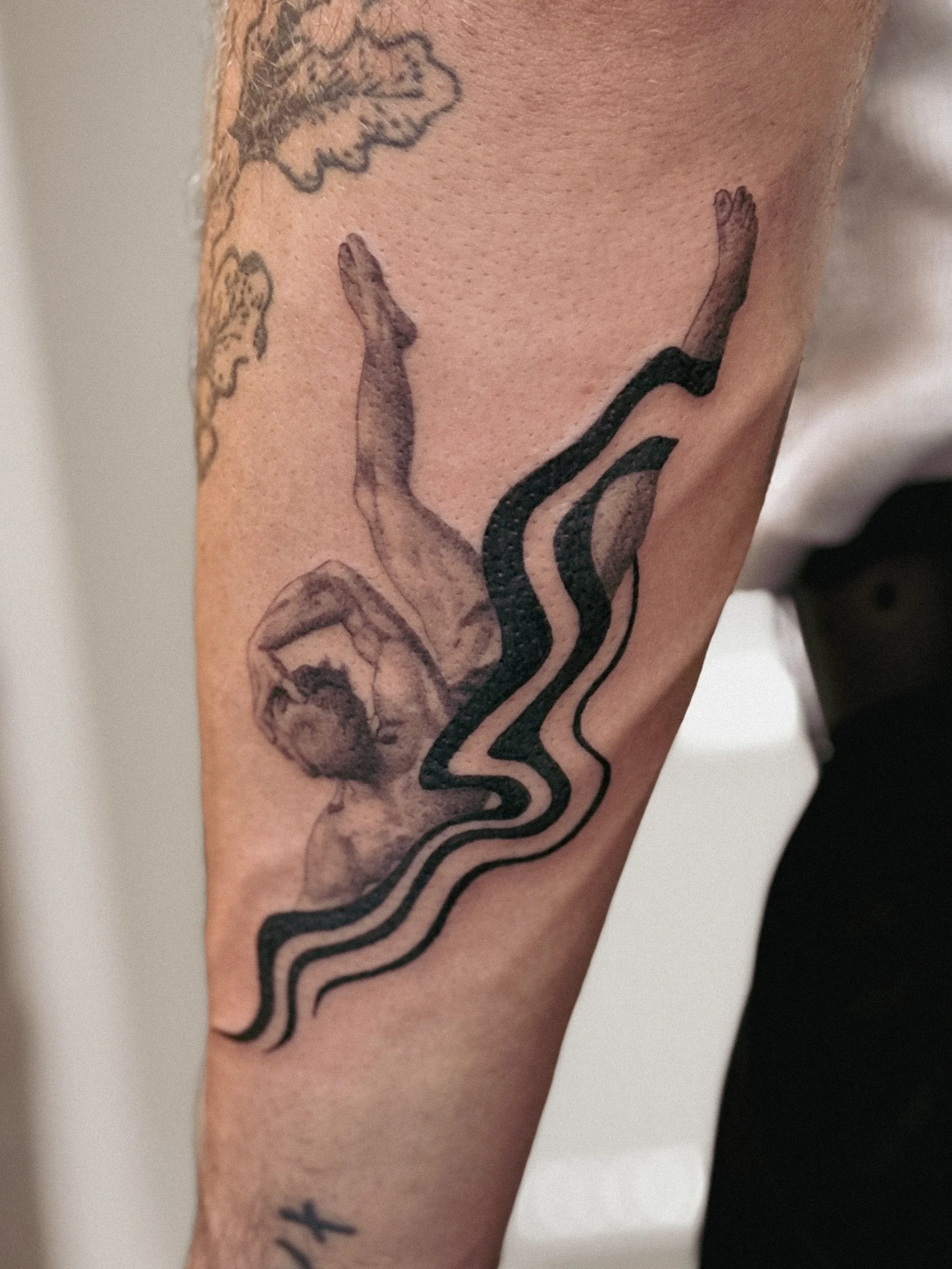 Tattoo of a woman's face with flowing hair and abstract black lines on a person's arm. ikarus tattoo

