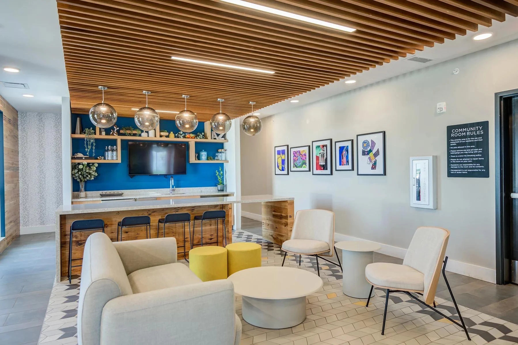 A modern community room with a high wooden slat ceiling, contemporary furniture, and colorful artwork on the walls.
