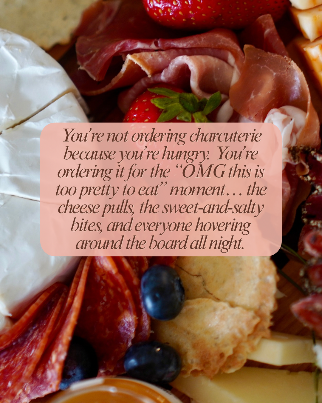 Close-up of a cheese and charcuterie board with strawberries, blueberries, cheese, cured meats, and crackers.