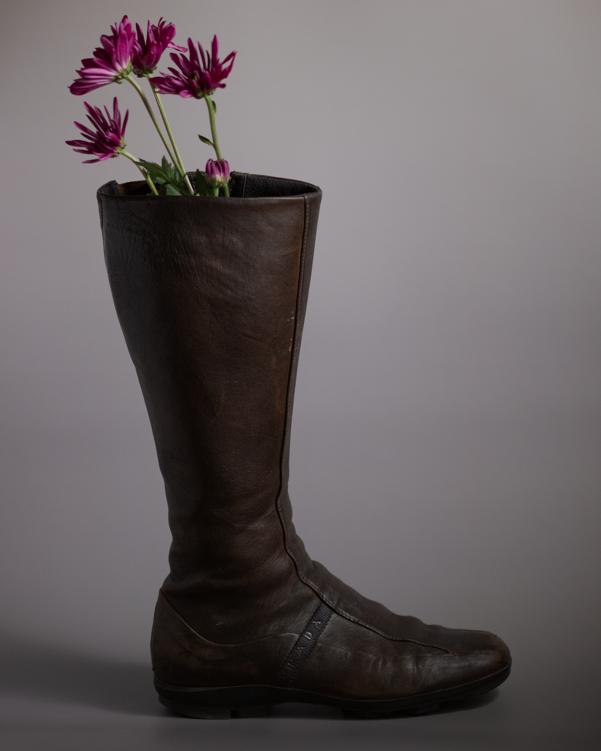 Editorial product photography of a brown Prada leather boot with pink flowers, created for ecommerce, branding, and visual content by mothers milk studio.