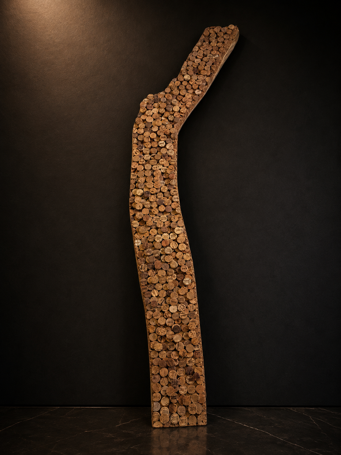 A large artwork shaped like a diagonal 'Y' made of numerous wine corks, mounted on a black wall.