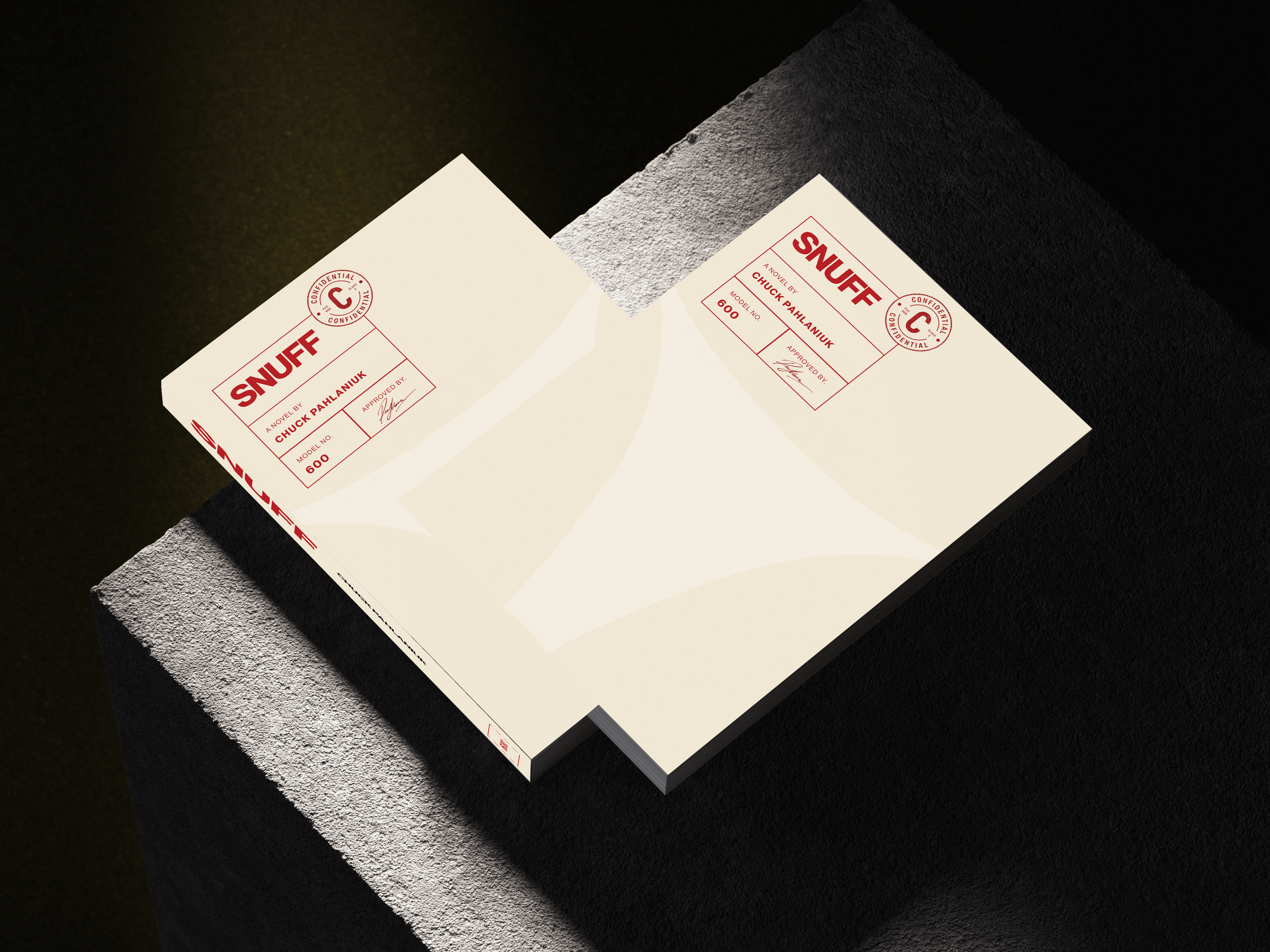 Close-up of a booklet titled 'SNUFF' with a red and white label, lying on a textured gray surface against a black background.