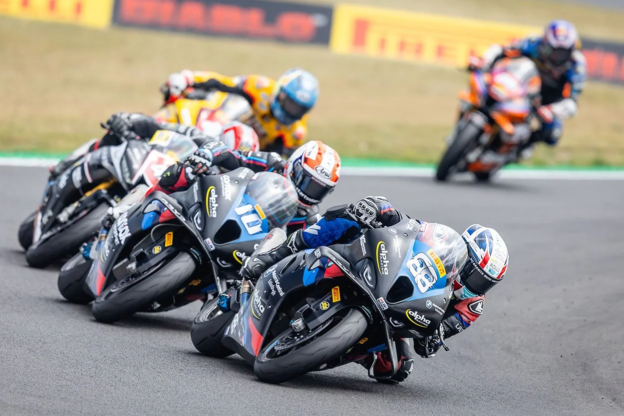 Motorcycle racers leaning into a turn on a race track during a competition.