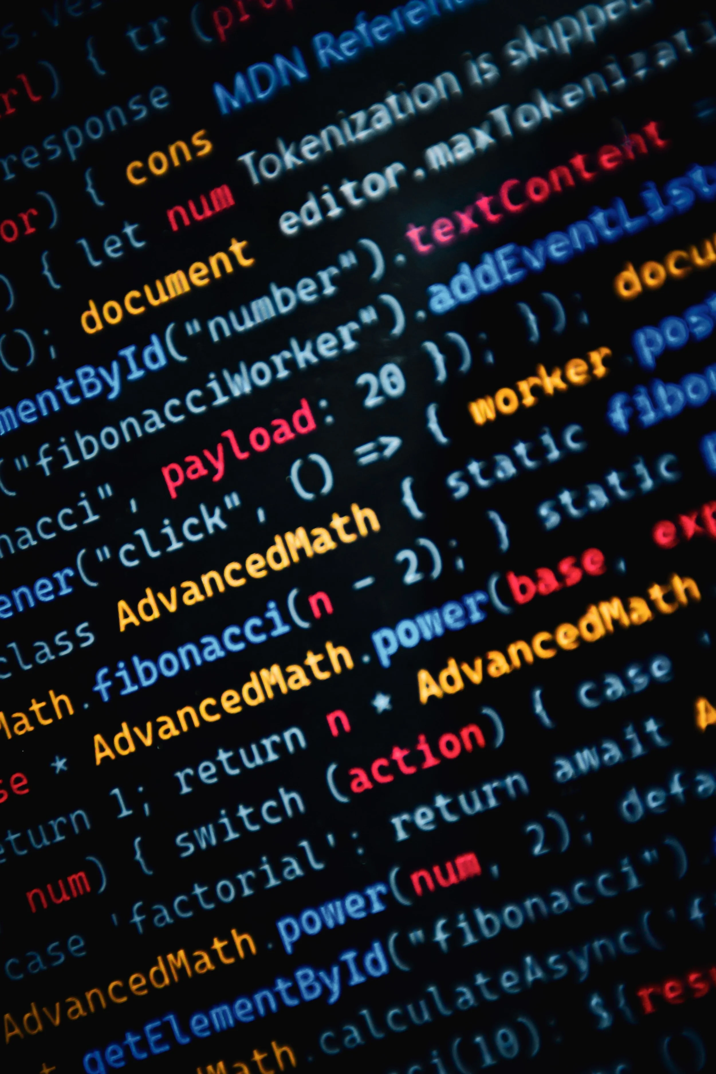 Close-up of colorful programming code displayed on a screen, featuring keywords such as 'const', 'document', 'payload', and 'math' in various colors like yellow, blue, red, and pink.