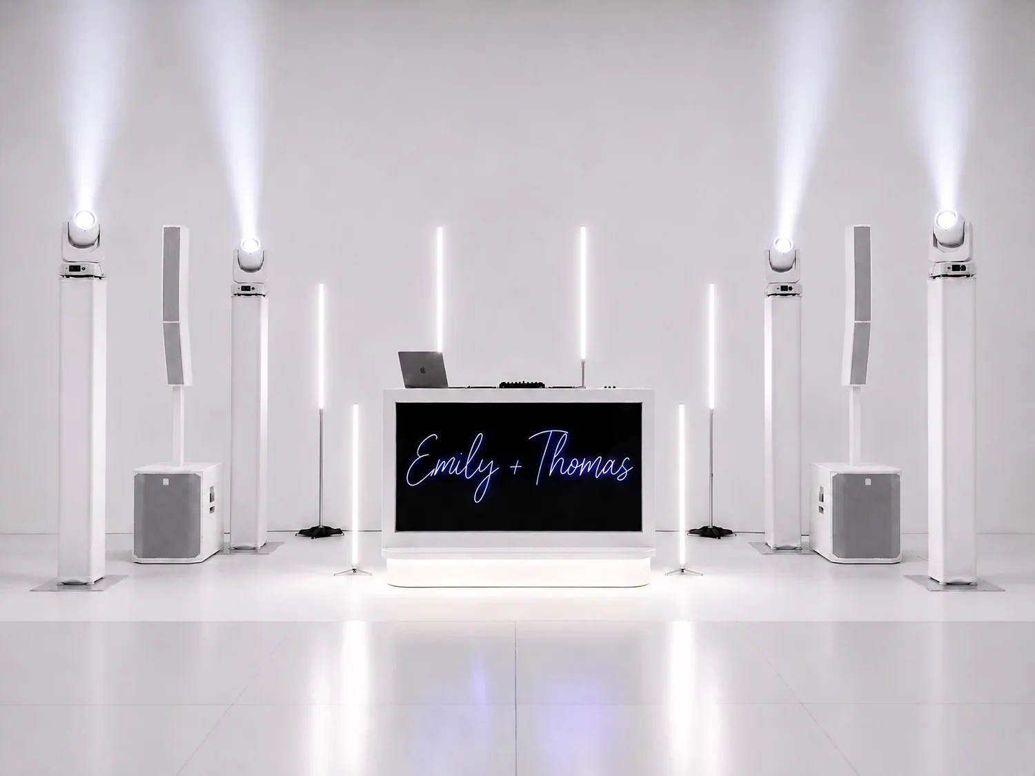 A minimalist wedding or event backdrop with a black screen displaying the names "Emily + Thomas" in neon script, surrounded by white vertical light bars, speakers, and a DJ booth with a laptop.