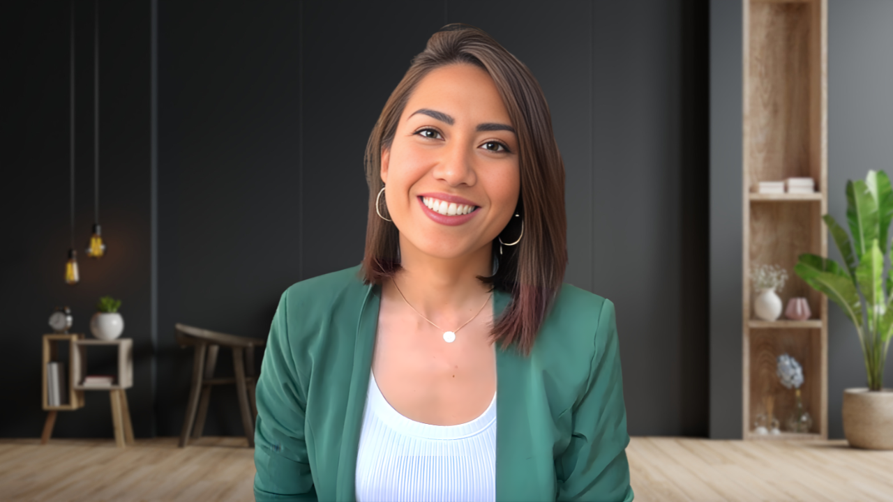A woman smiling in a modern interior with black walls, wooden shelves, and a potted plant.