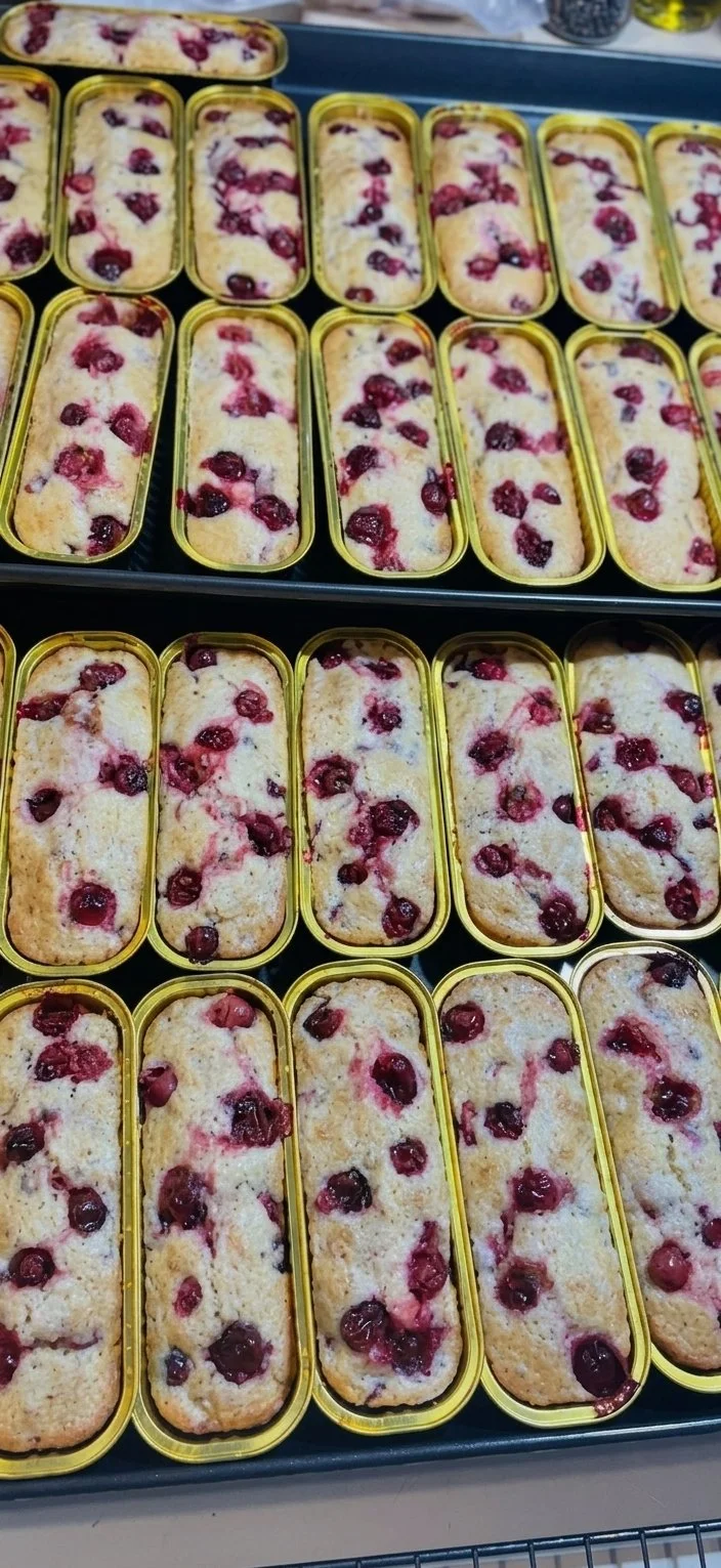 Multiple small rectangular tins of homemade cherry cobbler on a baking tray.
