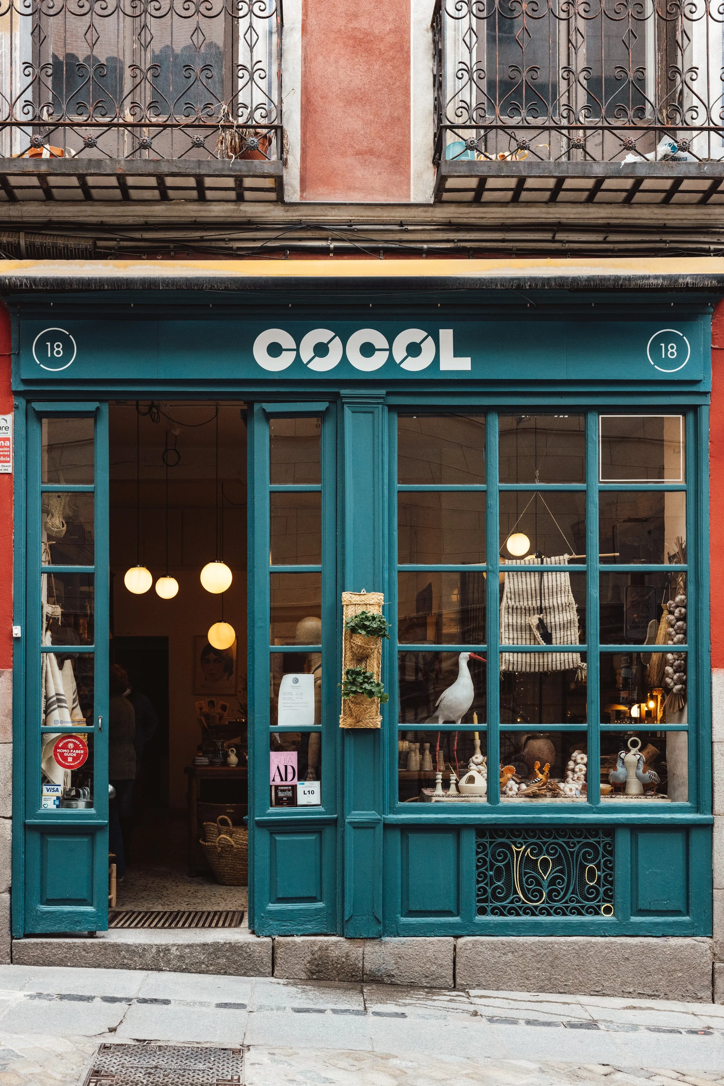 Storefront with blue painted wooden framework and large glass windows displaying decorative items, with a sign that reads "COOL" above the entrance.