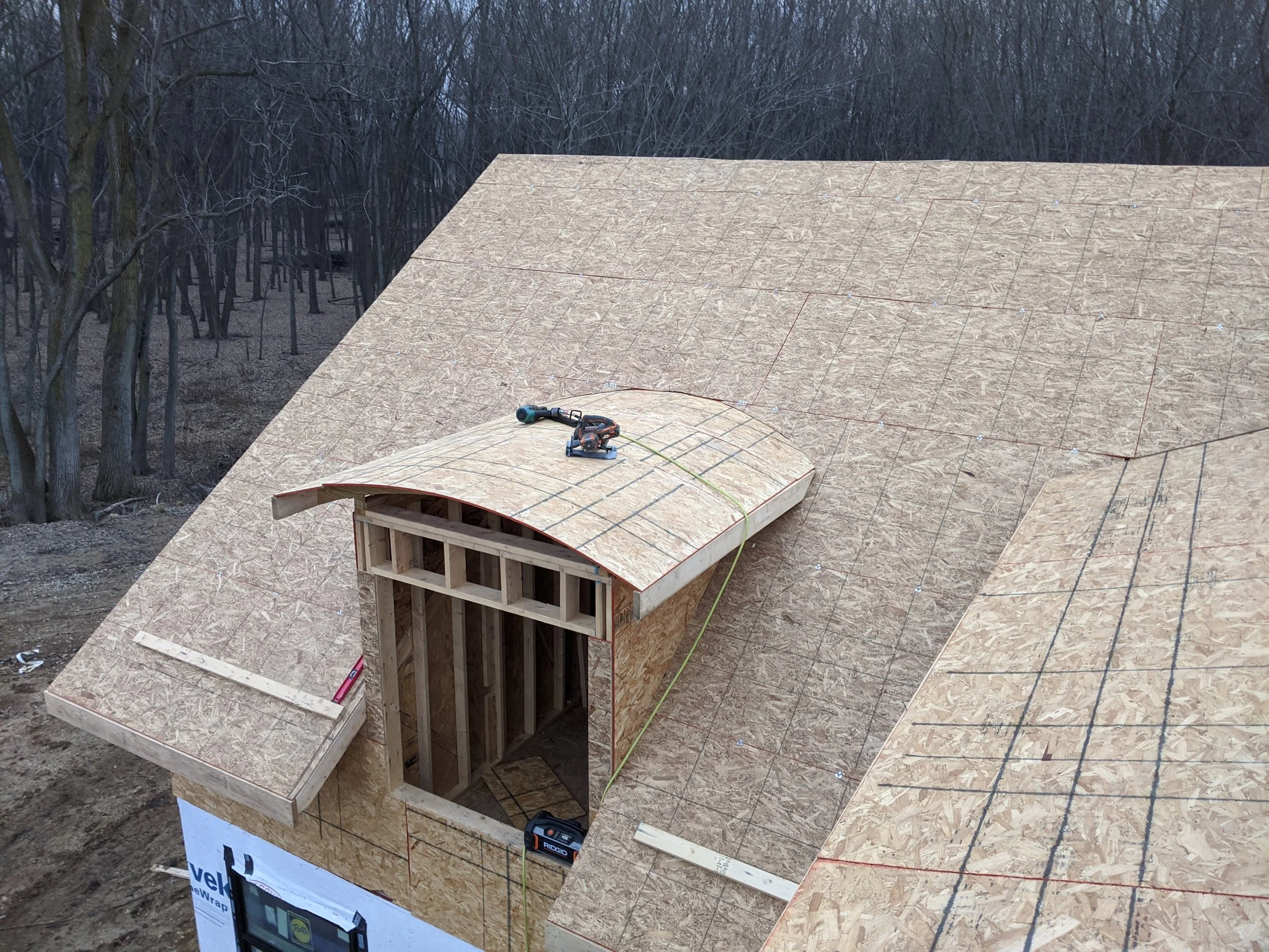 Sheathed eyebrow dormer on a custom home roof