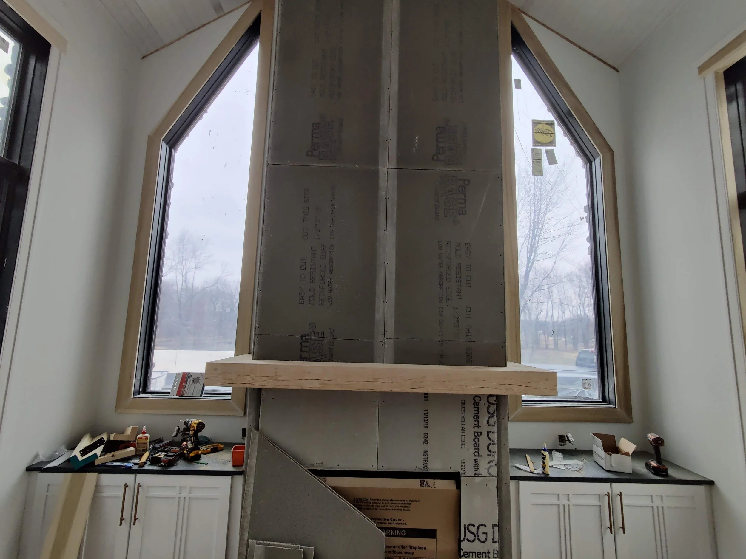 Chimney chase with custom wood mantel between windows