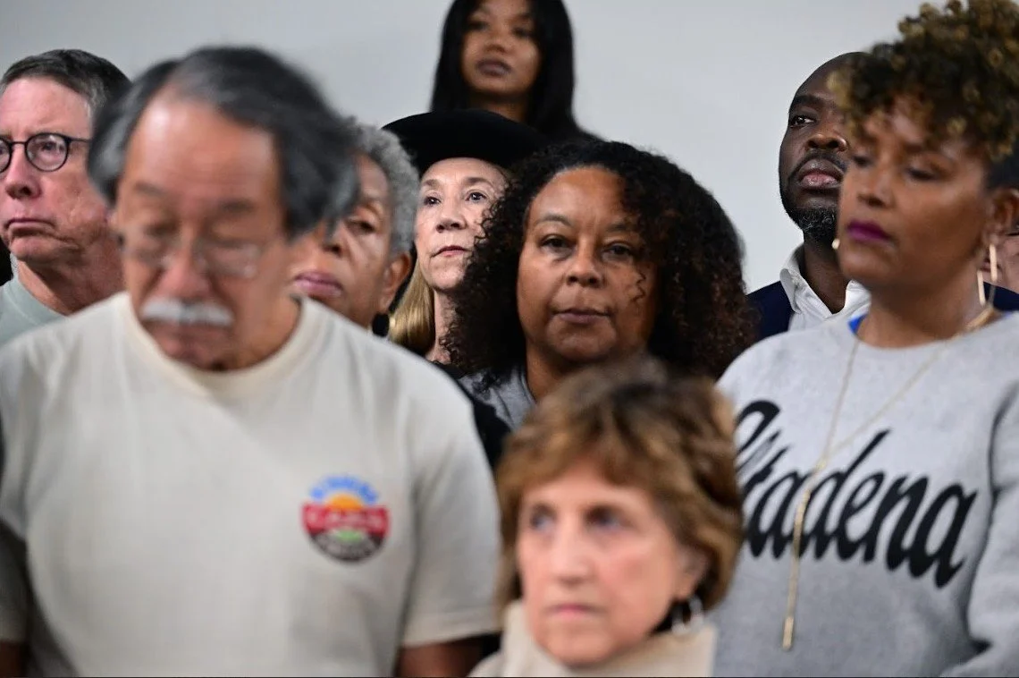 Group of community members listening attentively at an event, one wearing an 'Altadena' sweatshirt