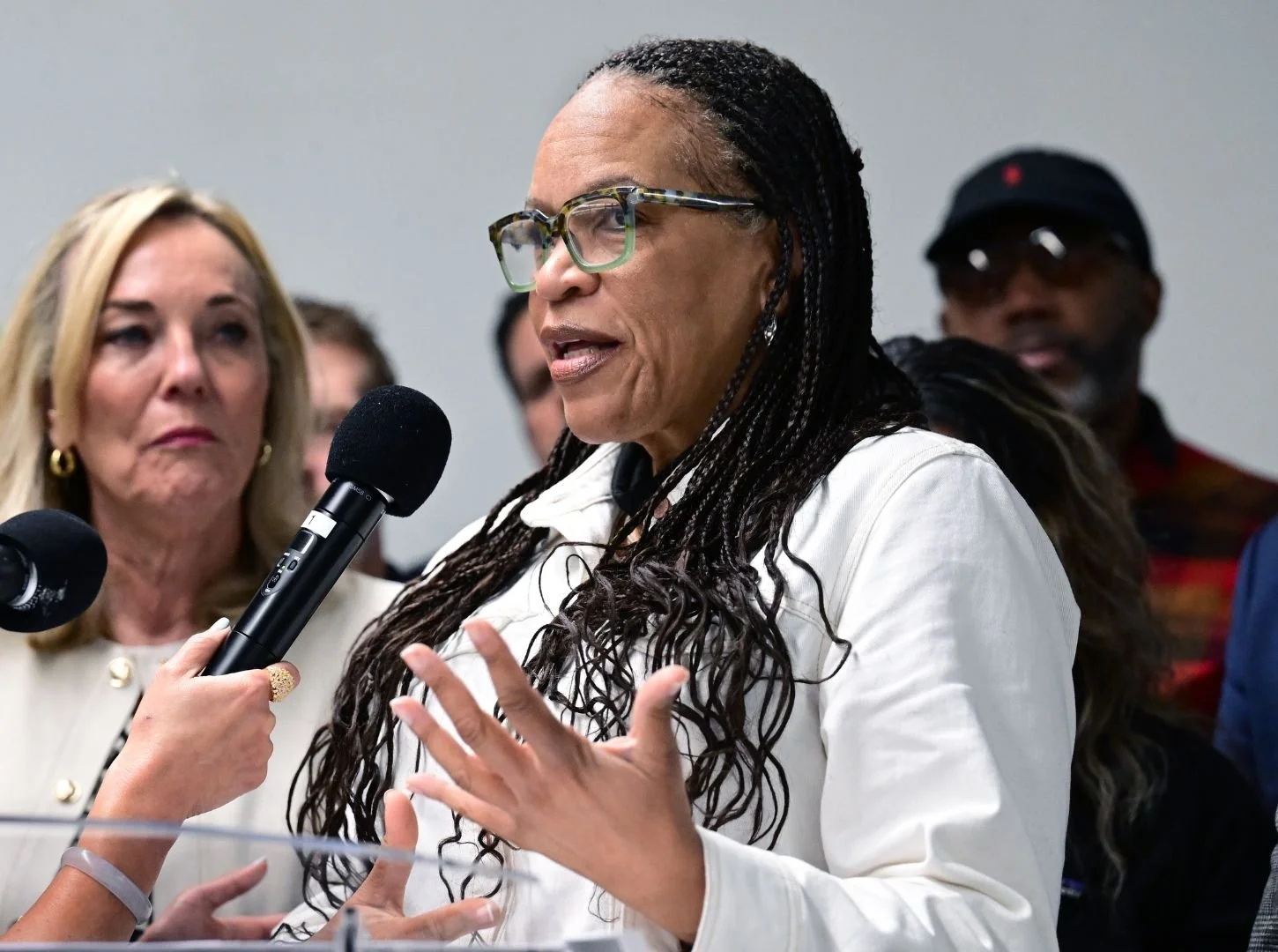 Rose Robinson speaking passionately at a podium, with Kathryn Barger in the background