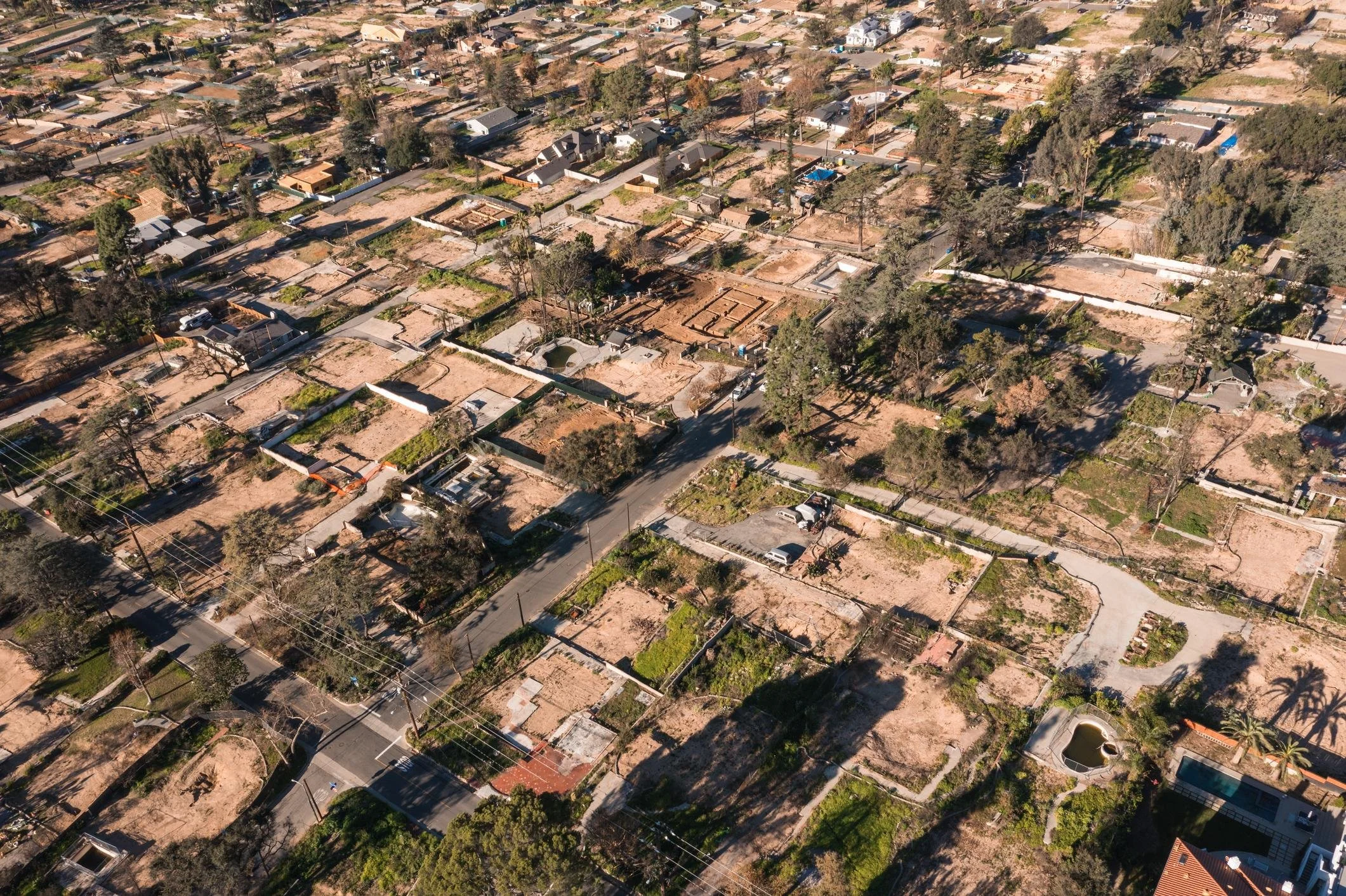 Aerial view of a residential neighborhood with cleared home foundations after wildfire destruction