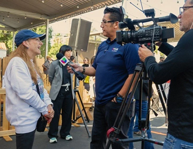 Man being interviewed by a news crew with a camera, outdoors
