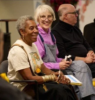 Three Eaton Fire survivors sitting together, smiling, at a community event