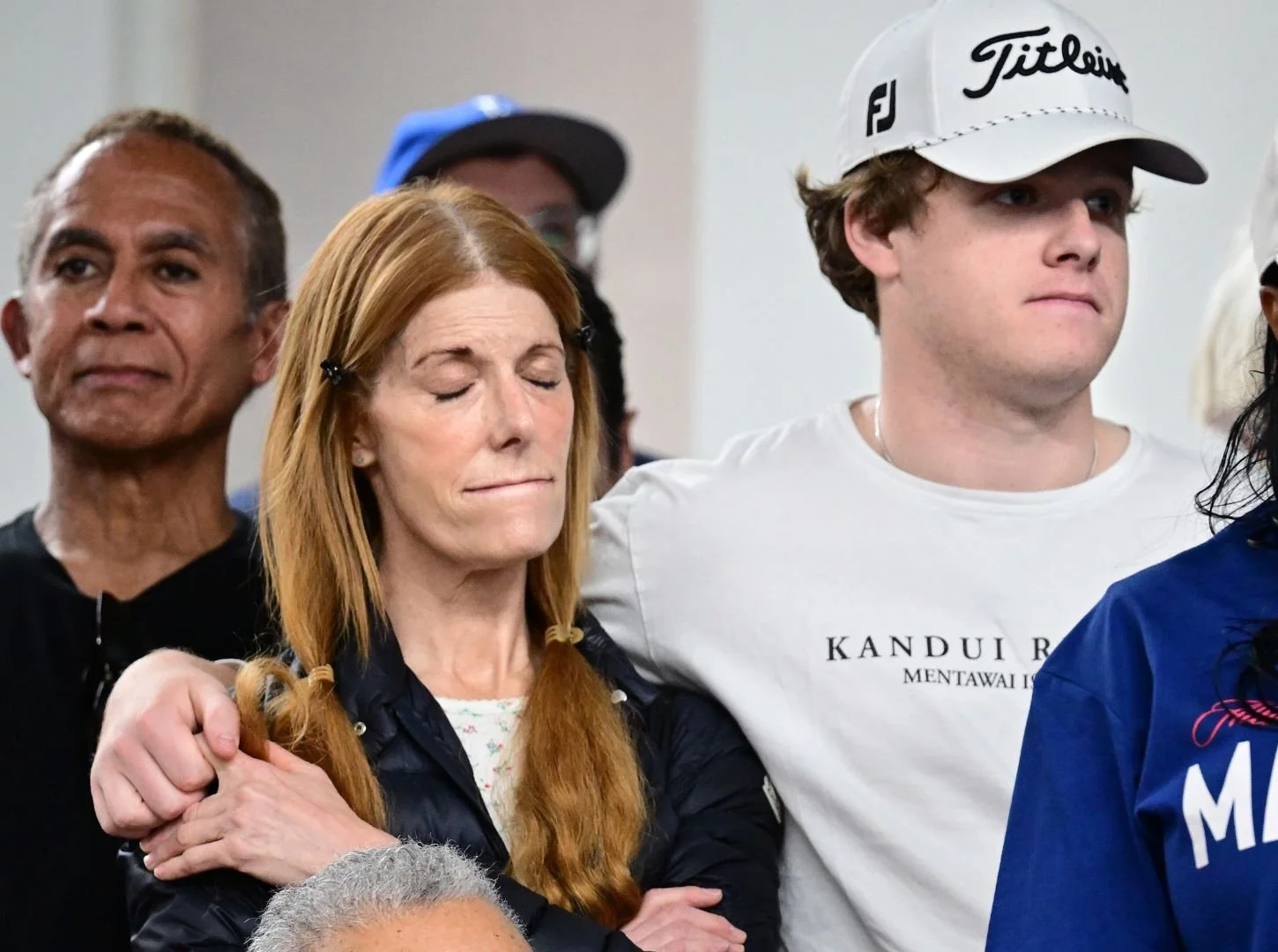 Woman with eyes closed, visibly moved, standing among a group of people