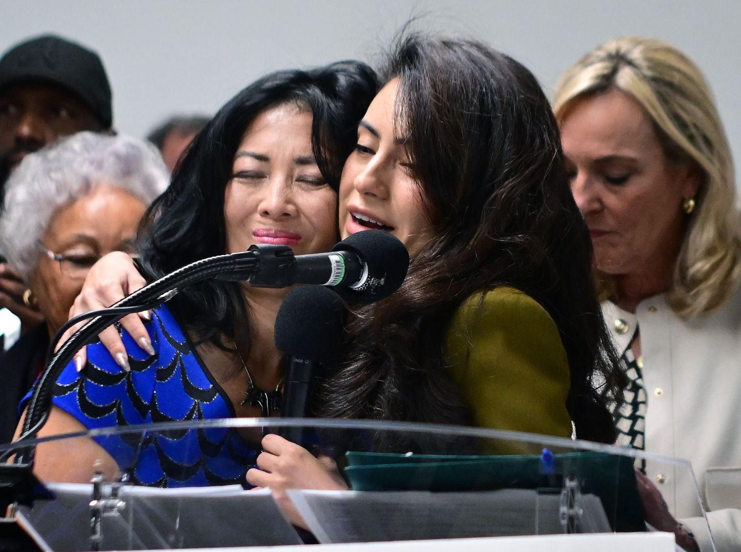 Joy Chen, Executive Director of EFSN, embracing Senator Sasha Renée Pérez at a podium with microphones