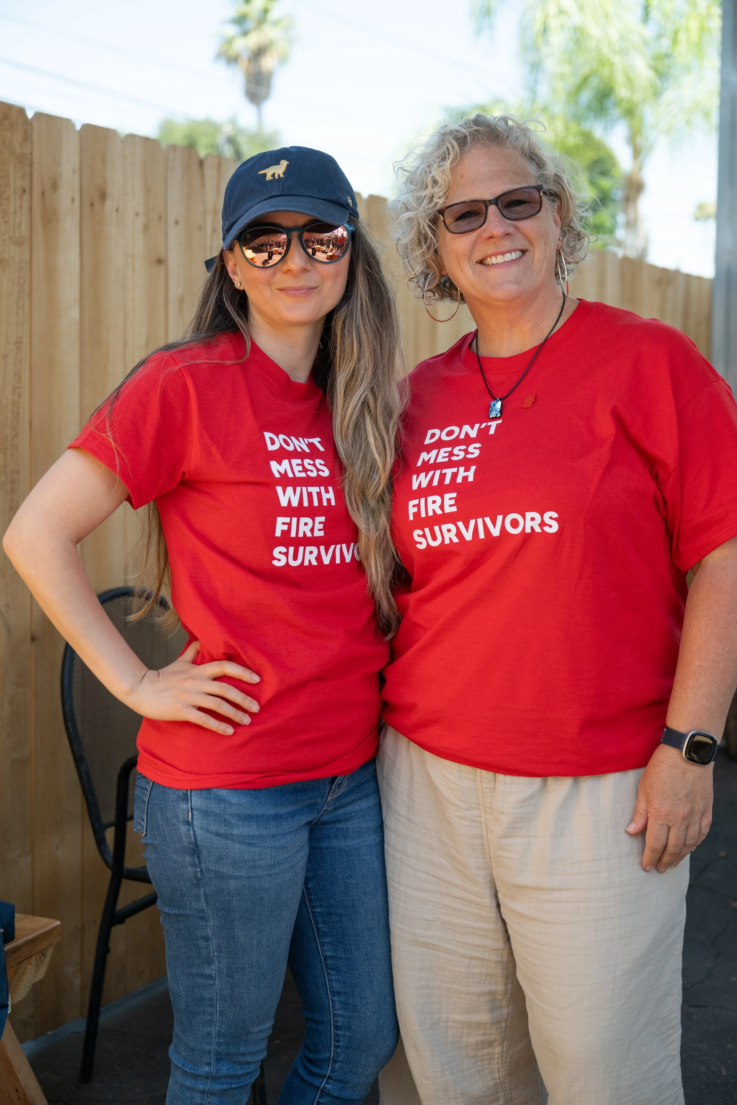 Two smiling fire survivors in red Don't Mess With Fire Survivors shirts