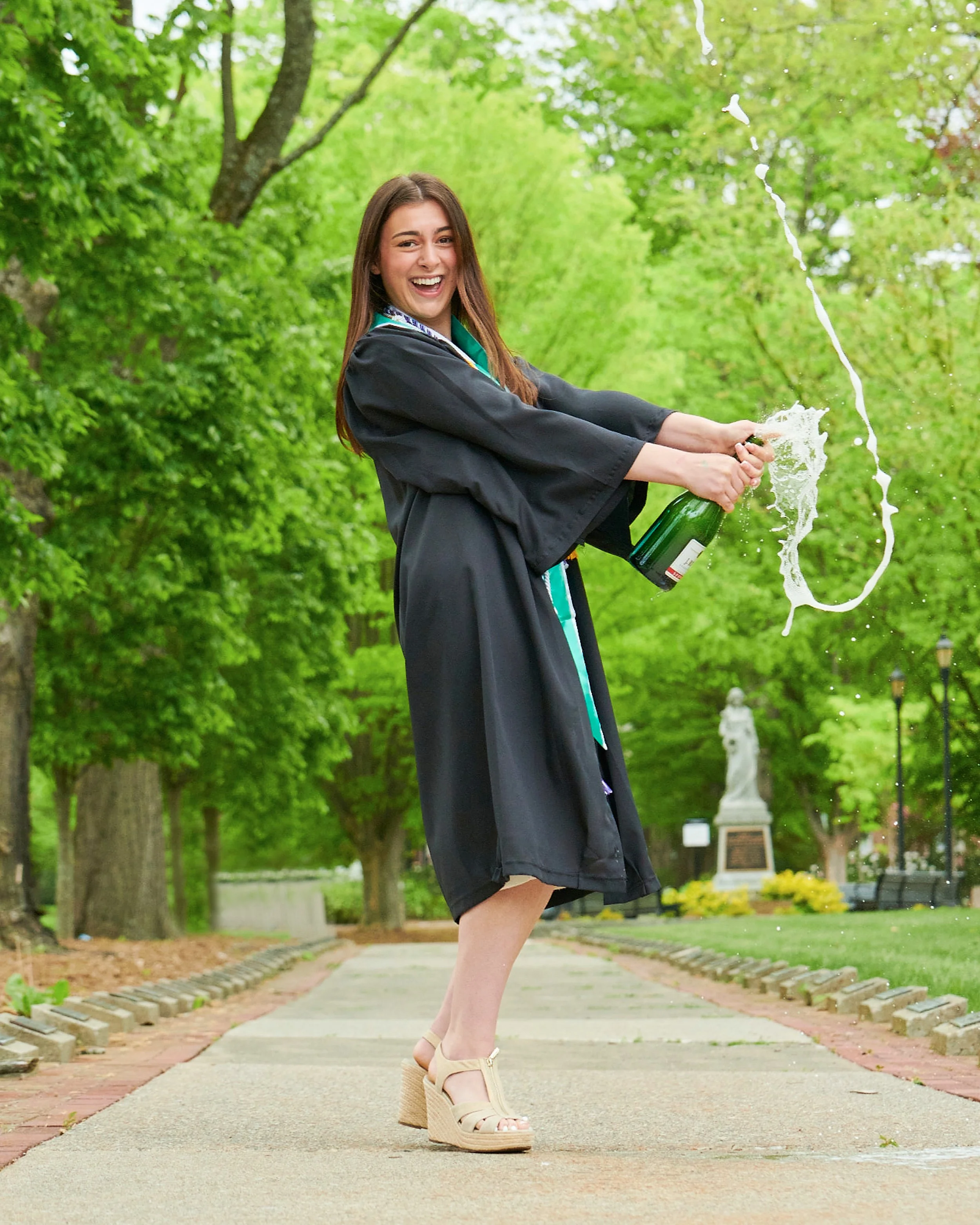 Graduate celebrating outdoors with champagne after graduation.