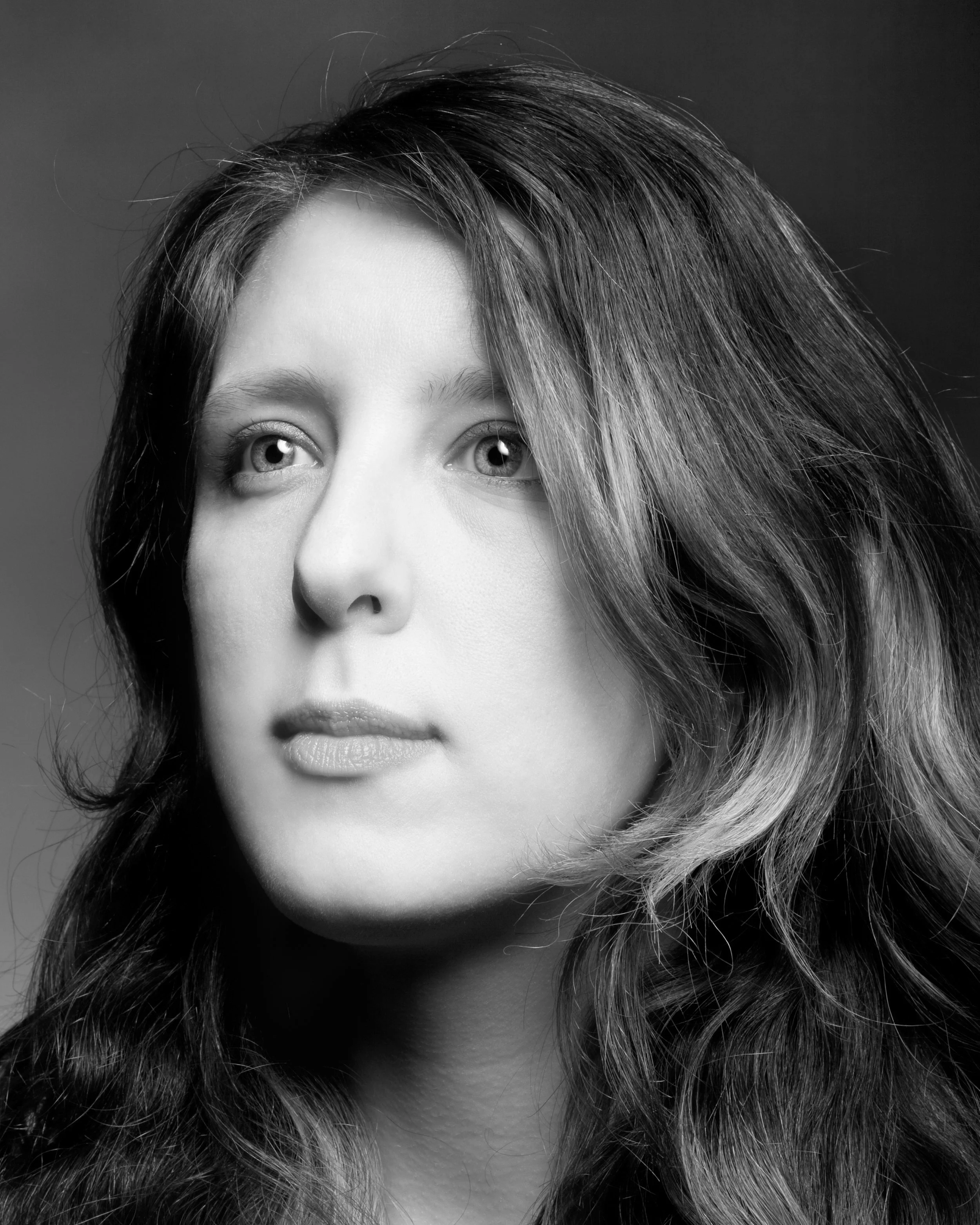 Black and white professional headshot of a woman on a dark background.