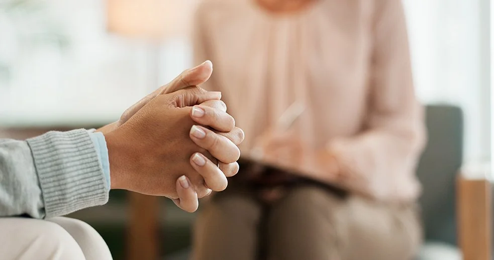 Deux personnes se tiennent la main dans une réunion ou un entretien à l'intérieur.