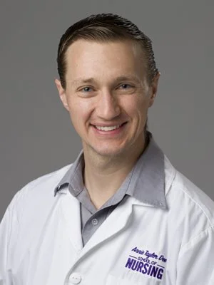 Smiling male healthcare professional wearing a white nursing coat against a gray background