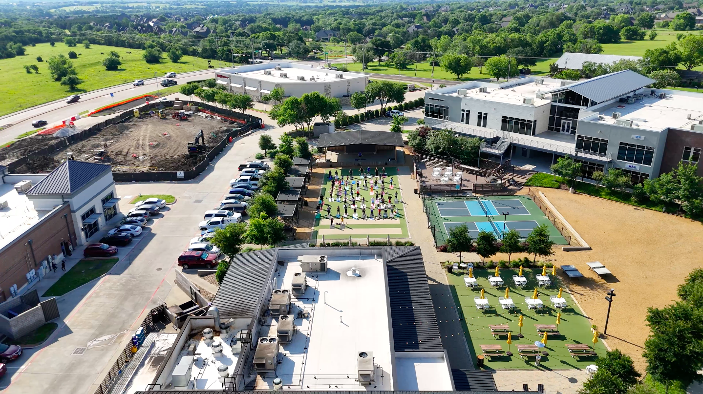 Aerial event photography of an outdoor venue with pickleball courts, lawn seating, and a crowd