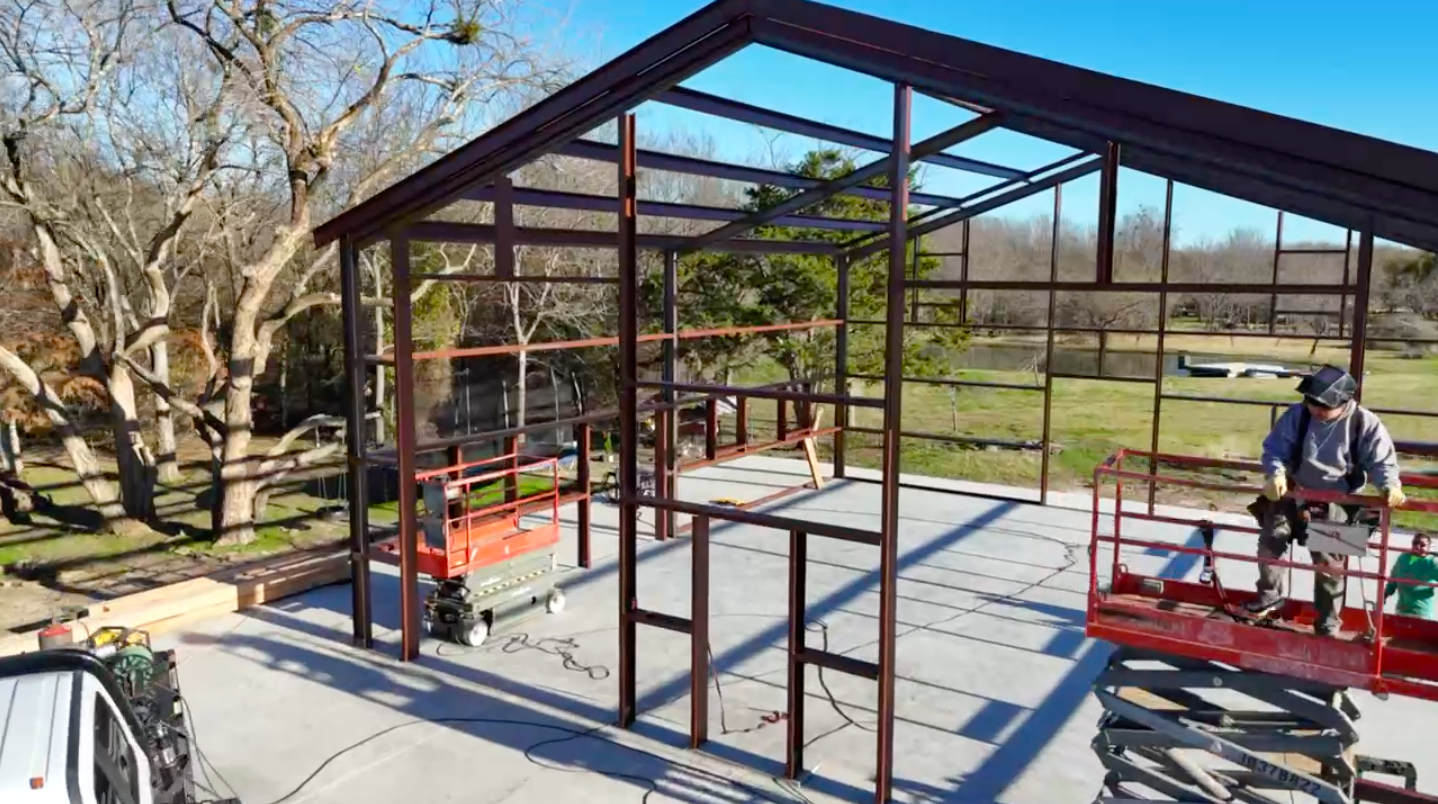 Aerial photo by Jacob Ortega, FAA-certified drone pilot, of a steel-frame build with scissor lifts on site