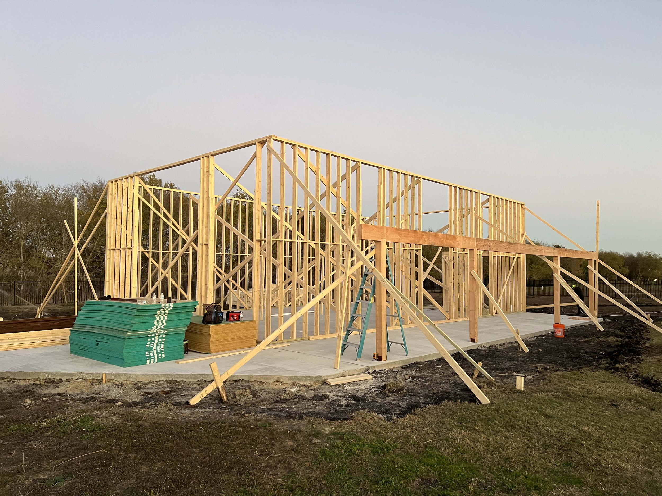Aerial construction photography of a wood-framed building on a new slab at dusk, documenting build progress
