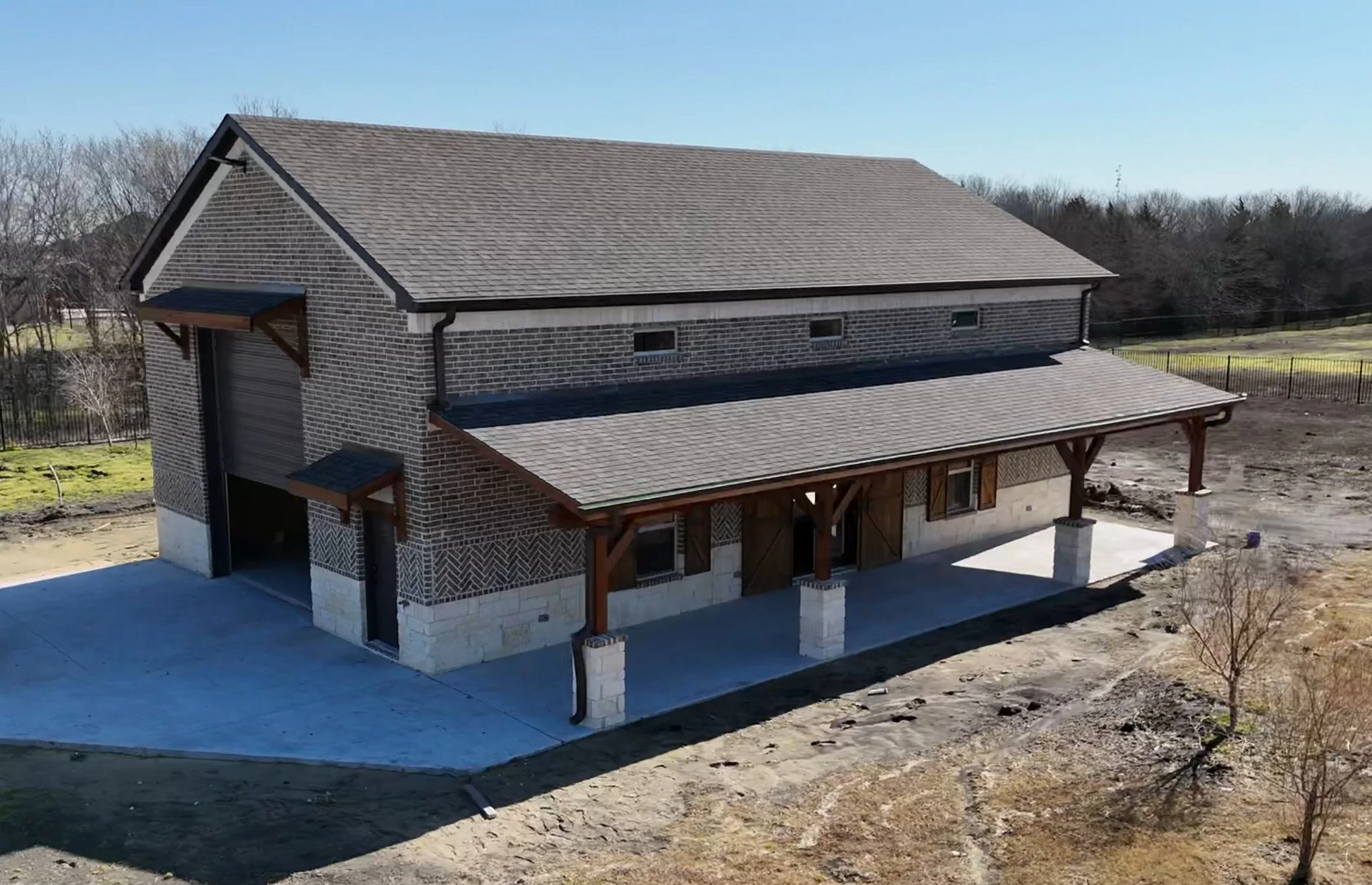 Drone photo of a newly built brick shop with a covered porch on a rural lot near Rockwall, TX