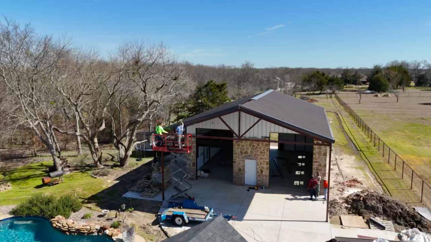 Drone photo of crews on a scissor lift finishing a stone and steel building, aerial construction documentation