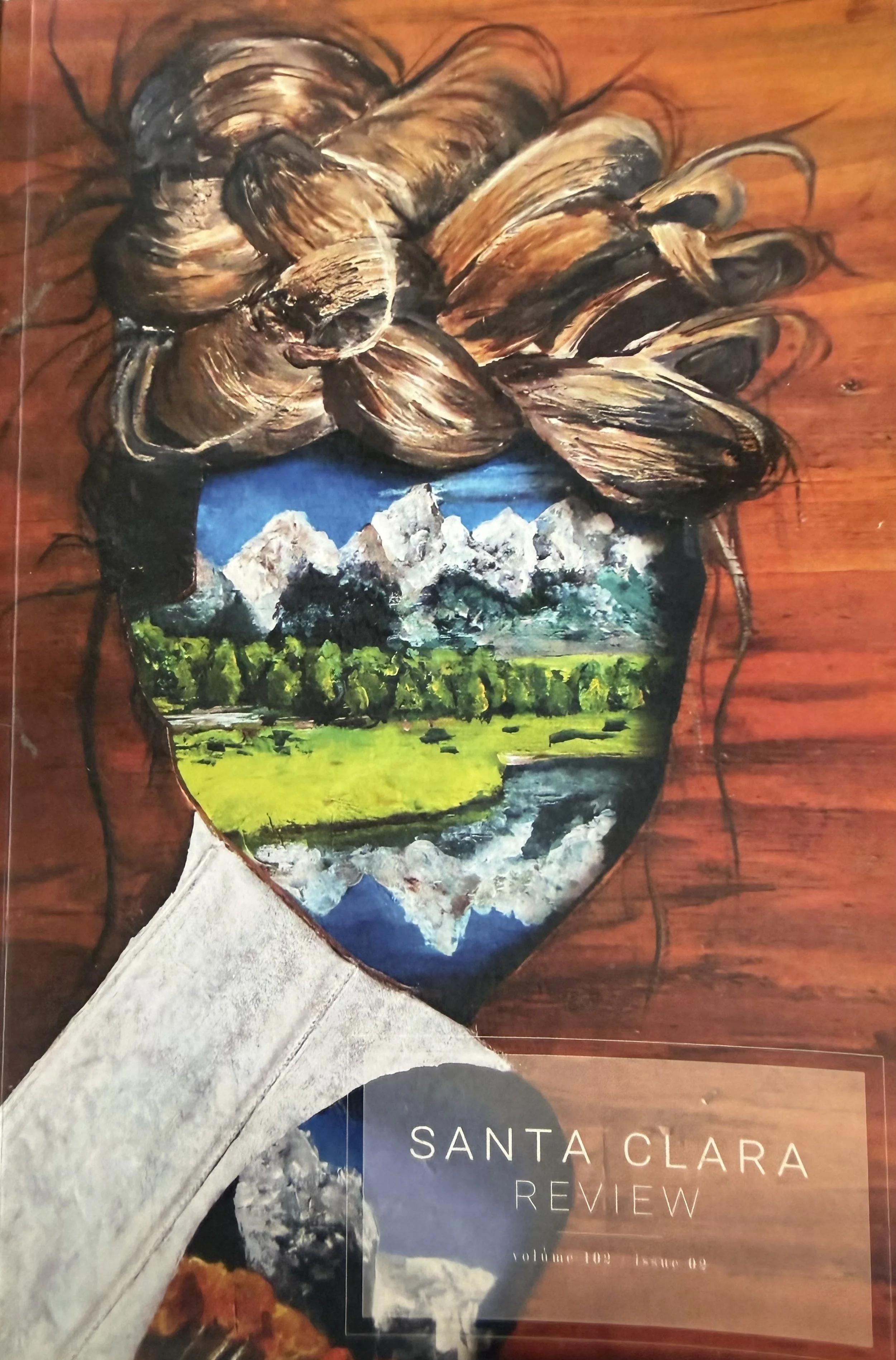 A collage with a painting of a woman's face, showing mountains, trees, and sky as her eyes and forehead. The artwork blends landscape and portrait elements