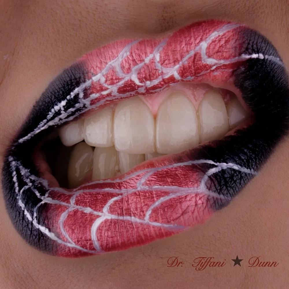 Close-up of lips with cannage pattern makeup, featuring a spiderweb design in red, white, and black, and teeth visible in the open mouth. The image includes text: Dr. Tiffani Dunn.