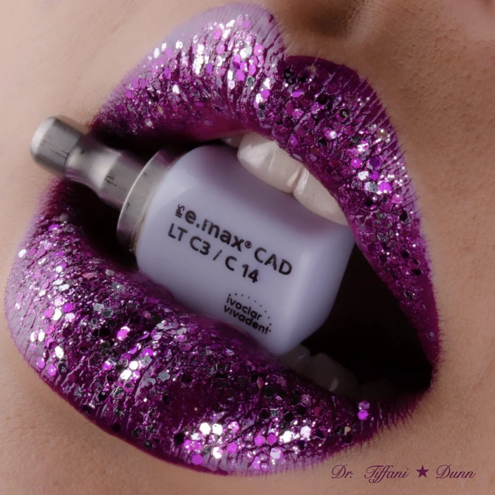 Close-up of lips with purple glittery lipstick holding a small white vial between teeth.