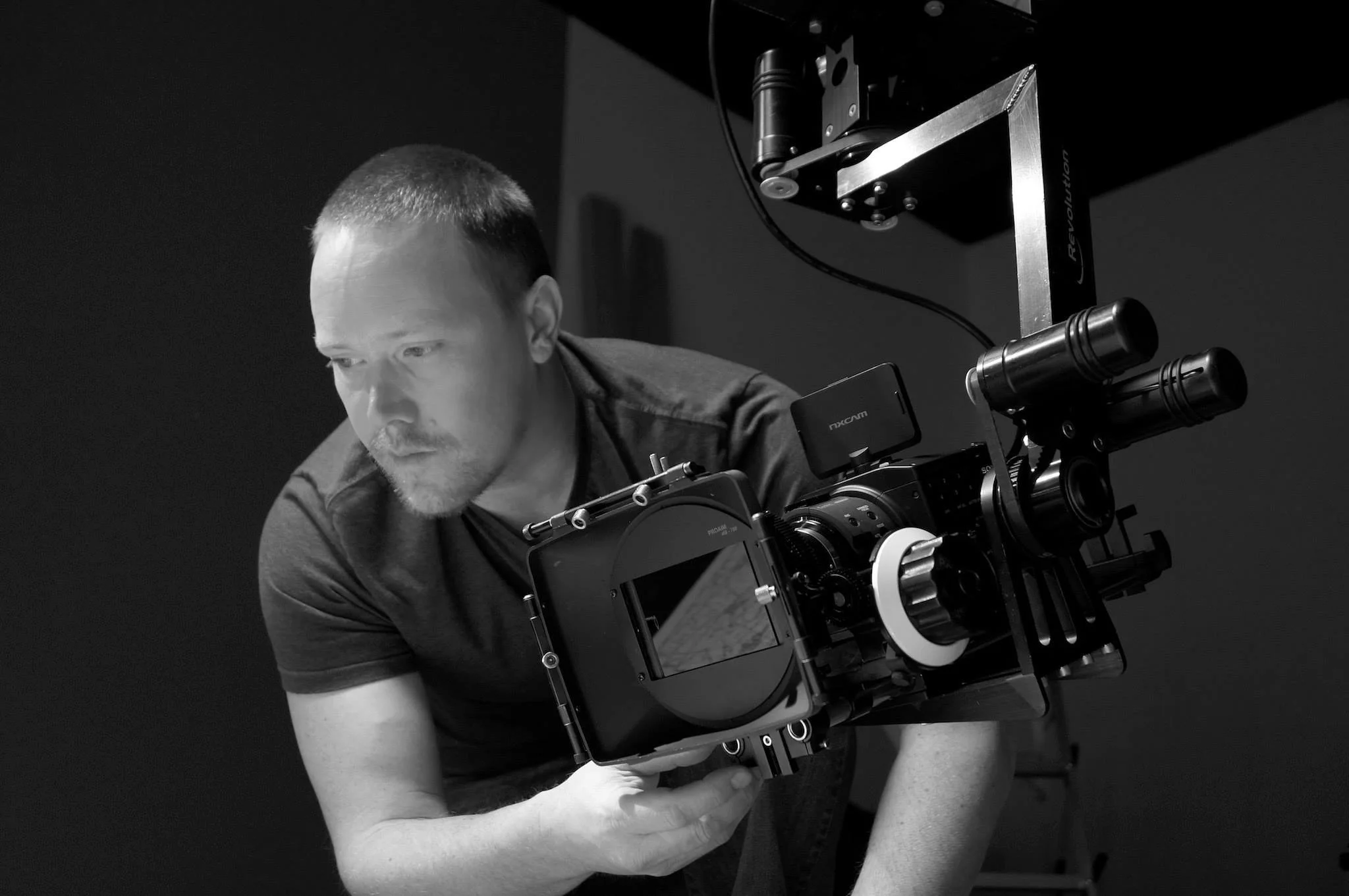 A person on a film set, adjusting a professional camera on a rig.
